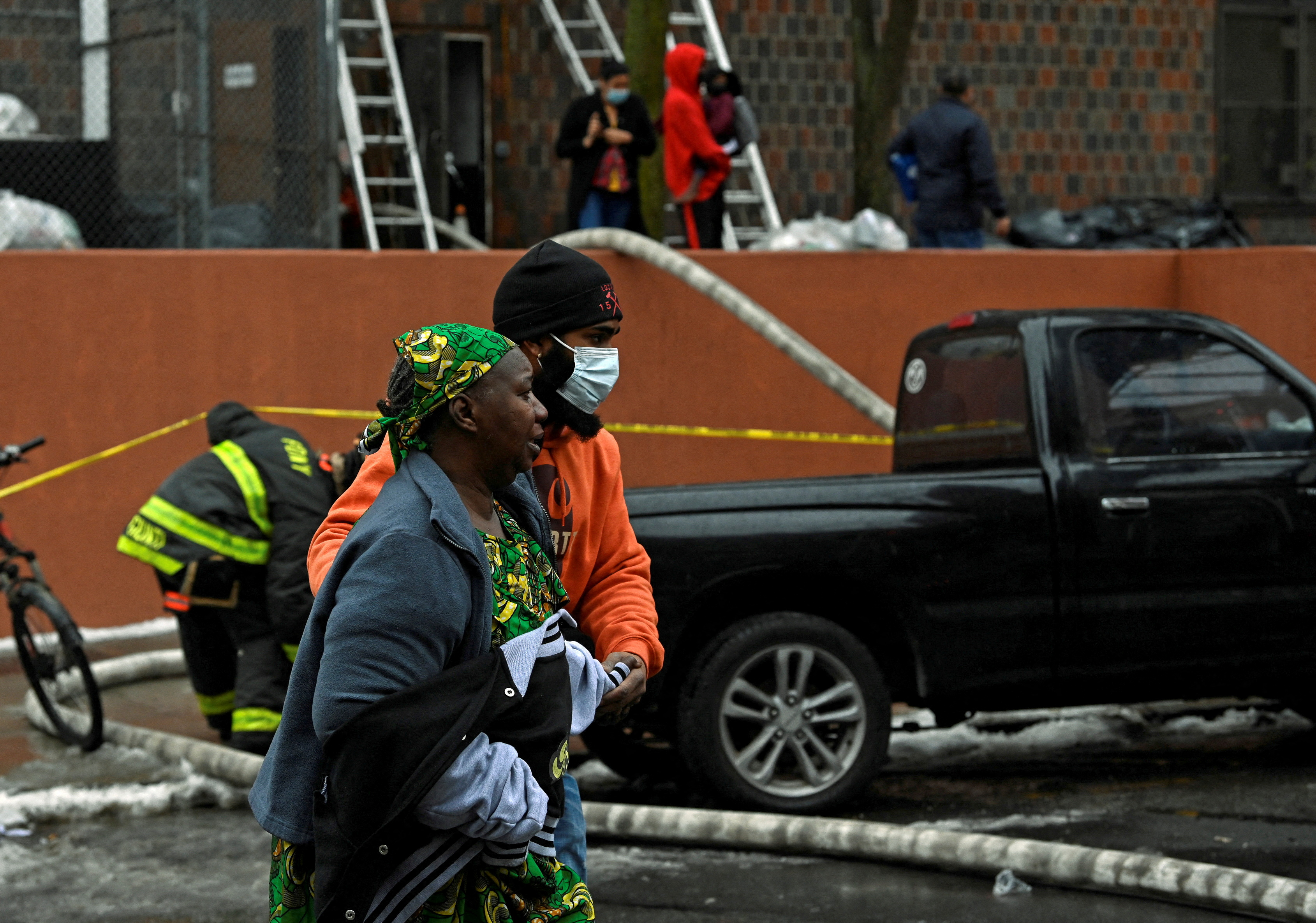 People walk at the scene of a fire in Bronx borough of New York City