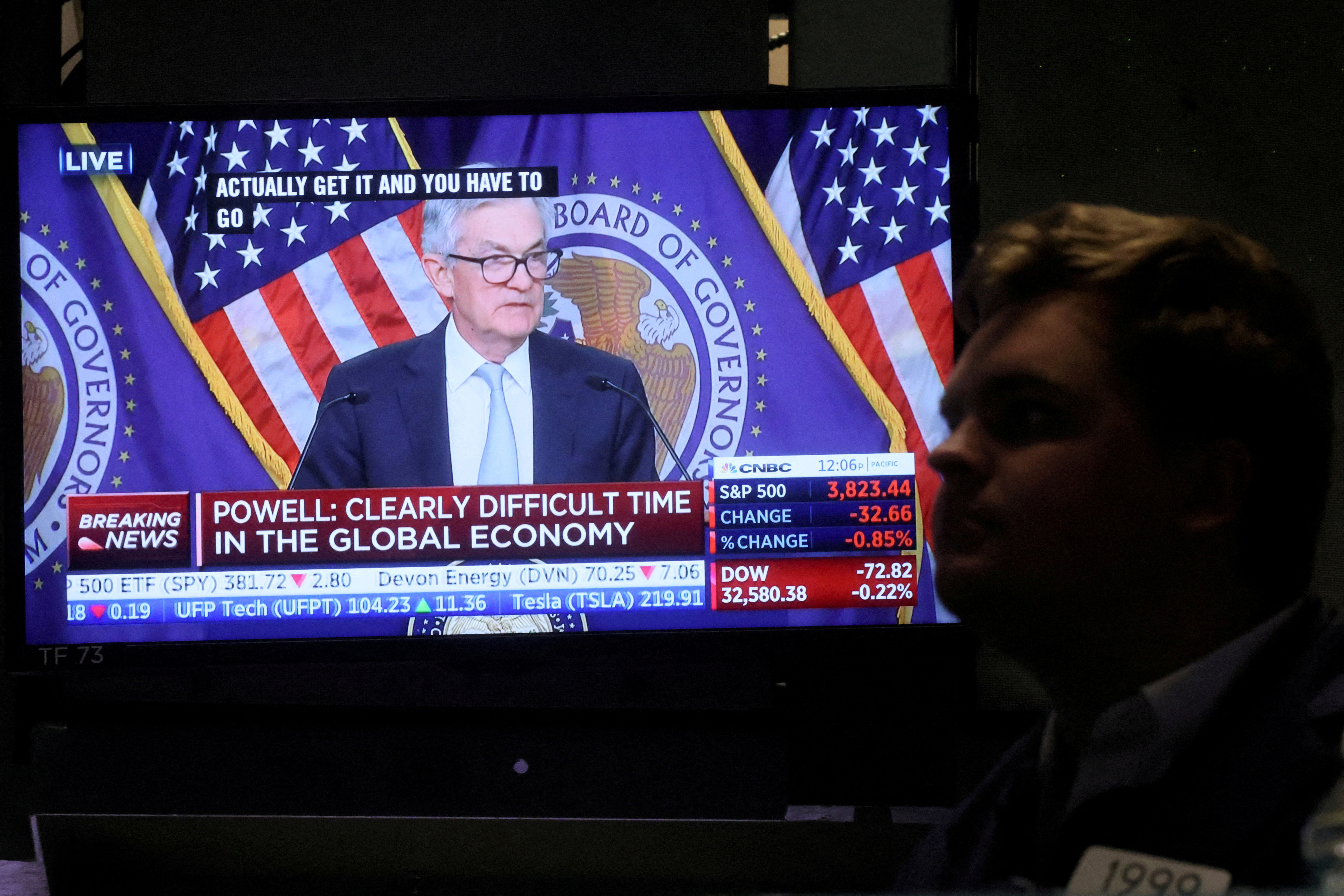 A screen displays Federal Reserve Chair Powell speaking as a trader works on the floor of the NYSE in New York, U.S.