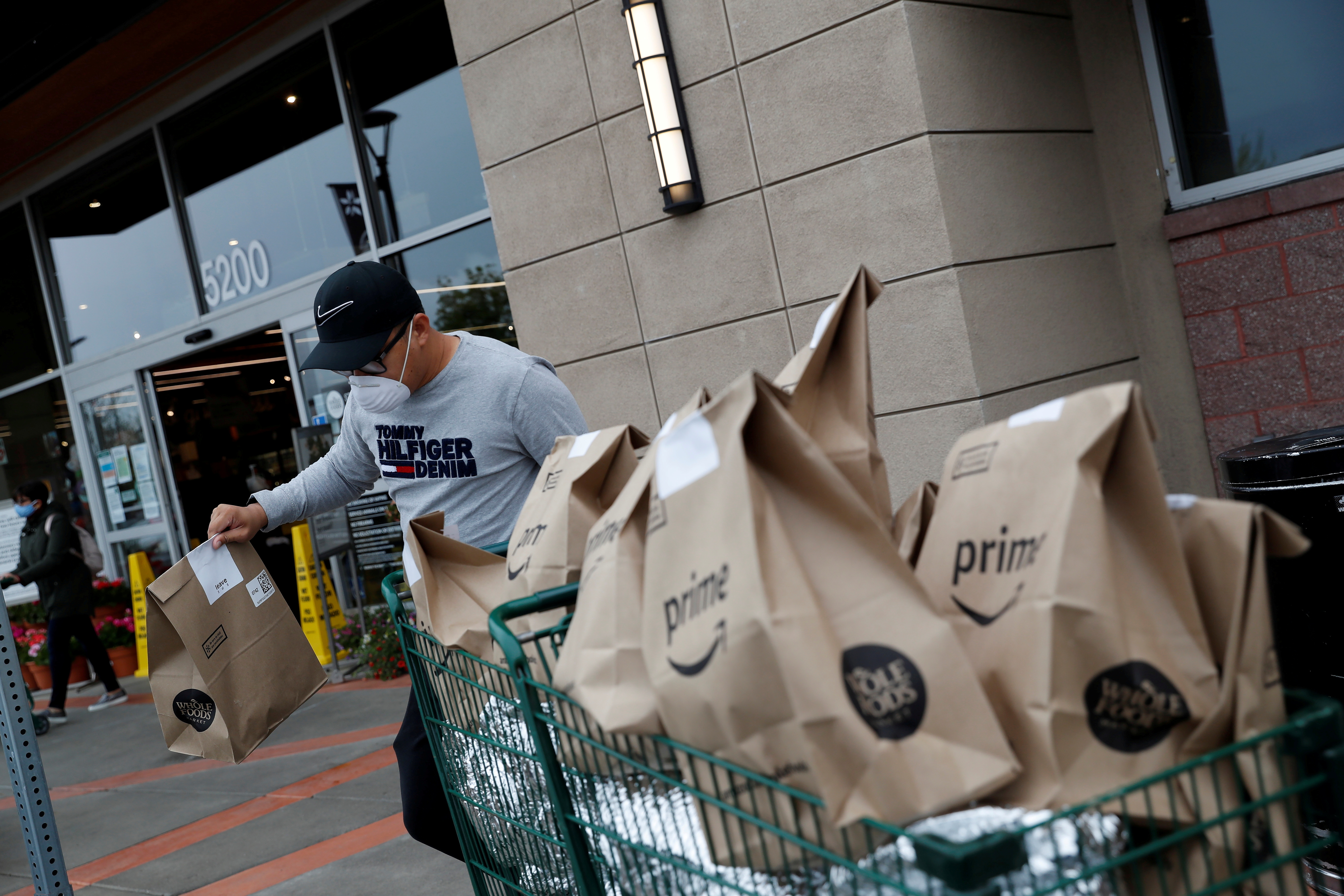 An independent contract delivery driver for Amazon Flex, wears a protective mask as he carries deliveries to his car near a Whole Foods Market, as spread of the coronavirus disease (COVID-19) continues, in Dublin, California, U.S., April 6, 2020. REUTERS/Shannon Stapleton/File Photo