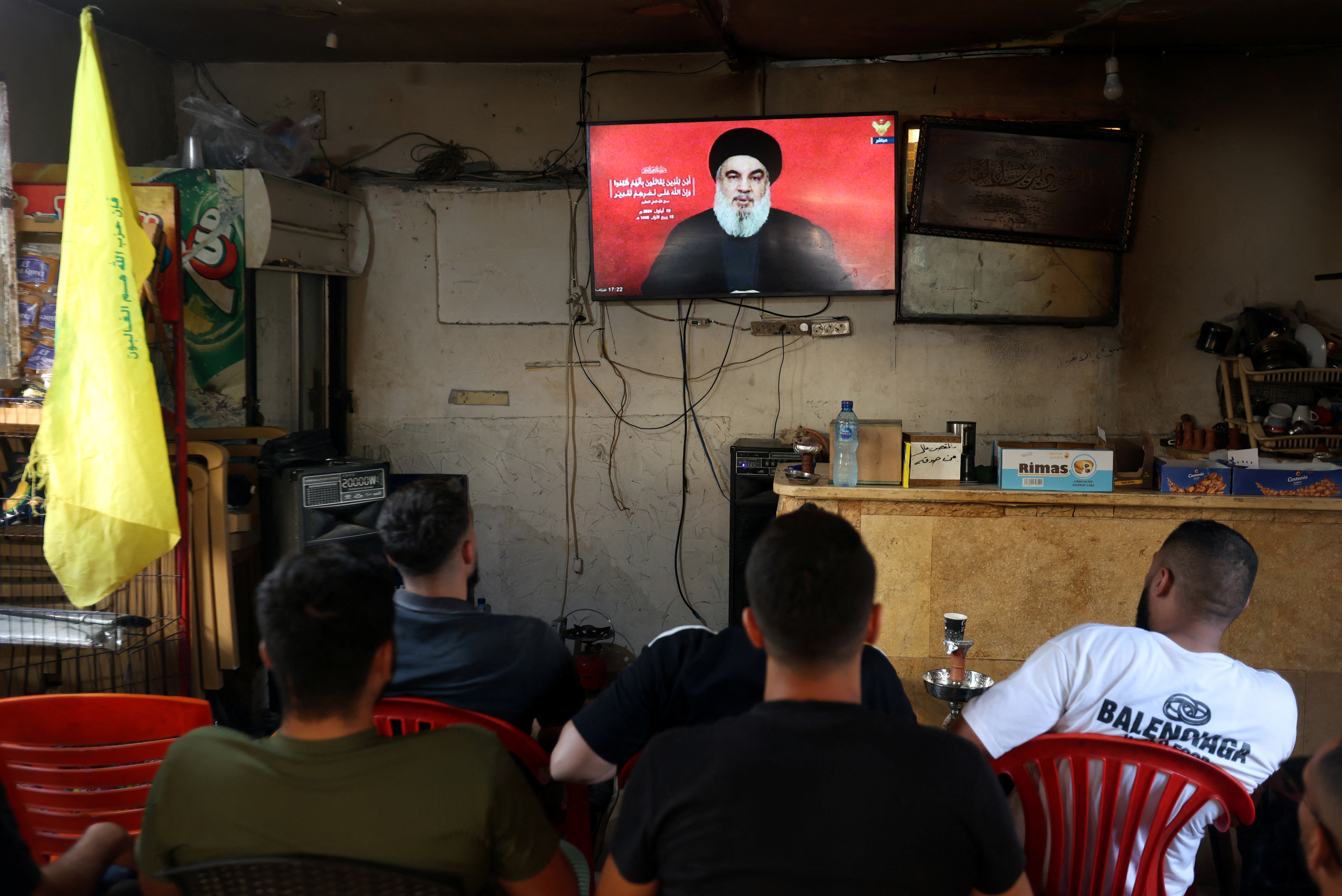 People watch Lebanon's Hezbollah leader Sayyed Hassan Nasrallah delivering a televised address, as they sit at a cafe in Sidon