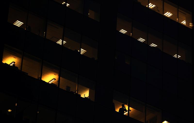 A man talks on the phone as office lightning is seen through the windows of a building in downtown Buenos Aires, Argentina August 11, 2017. REUTERS/Marcos Brindicci