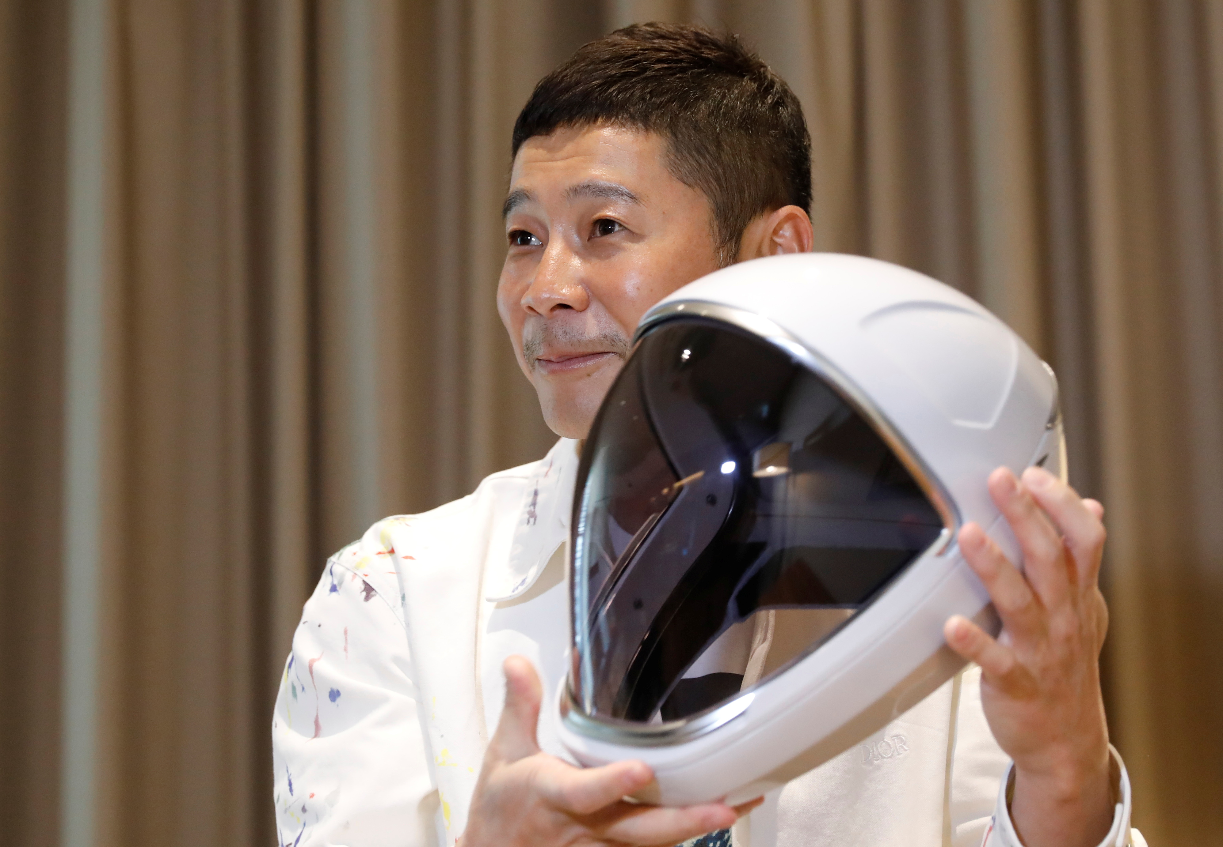 Japanese billionaire Yusaku Maezawa poses with a space suit helmet during an interview with Reuters in Tokyoo