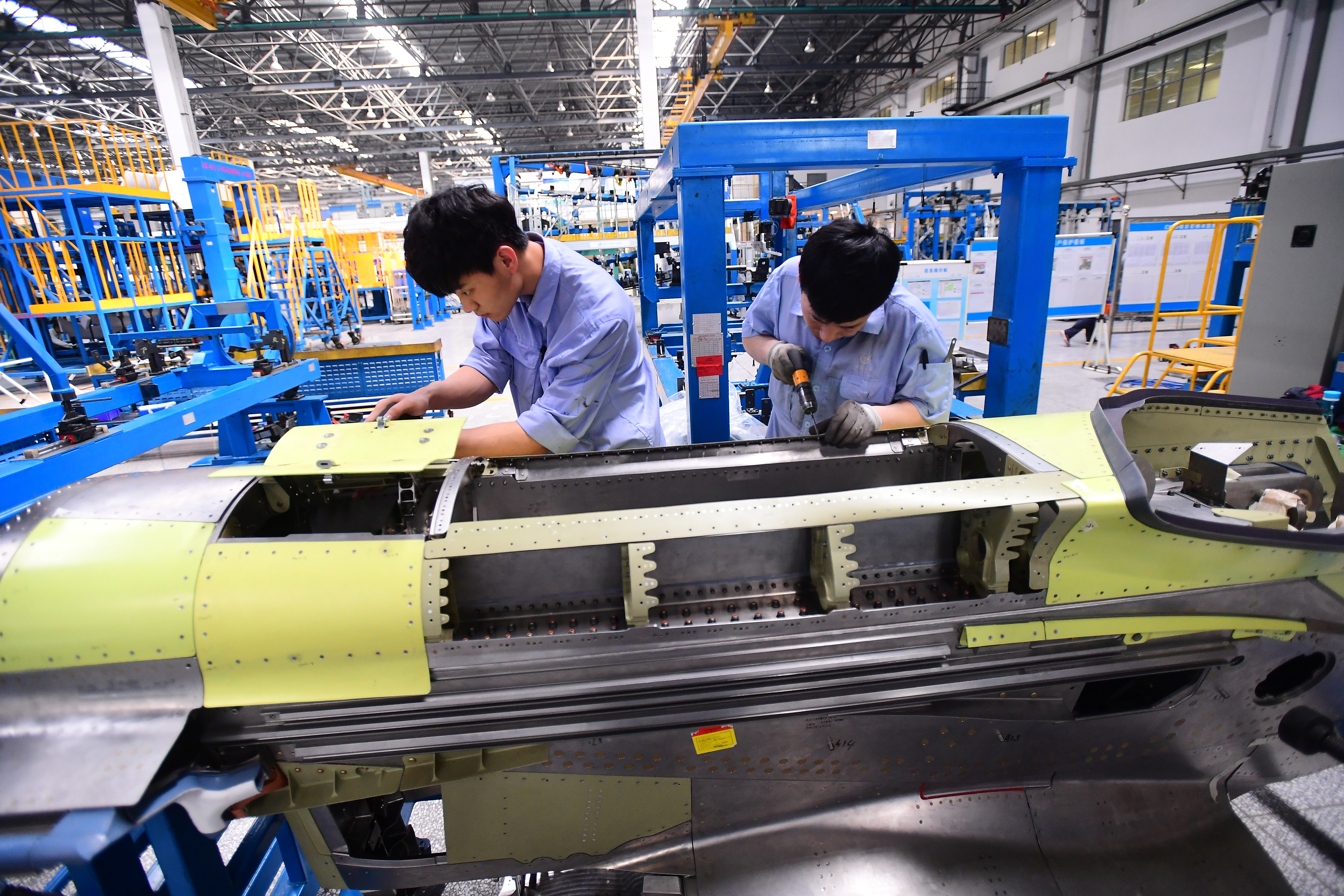 Workers assemble part of the engine assembly for China's self developed C919 passenger aircraft at a factory of Shenyang Aircraft Corporation in Shenyang