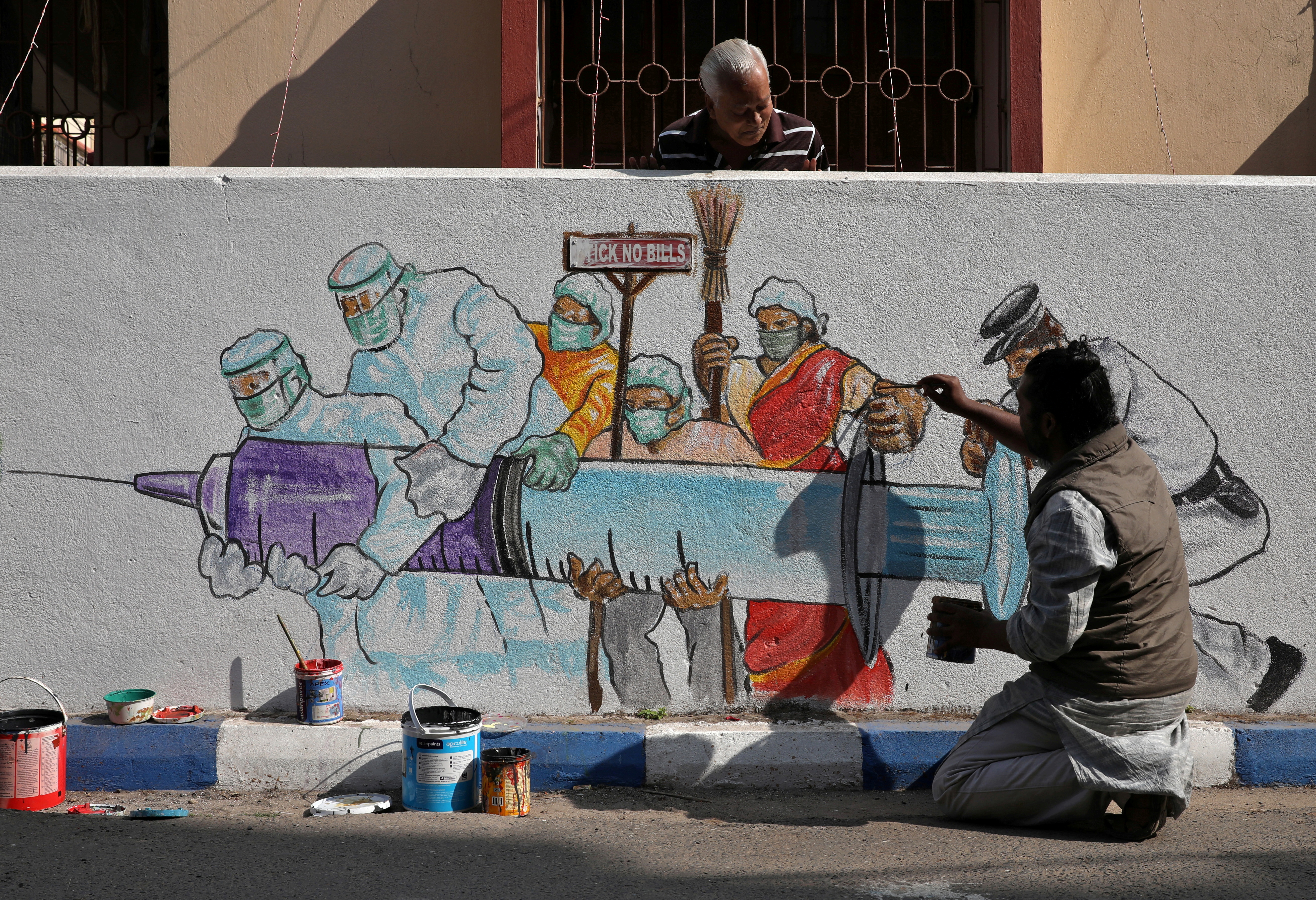 Man applies finishing touches to graffiti representing a vaccine in Kolkata