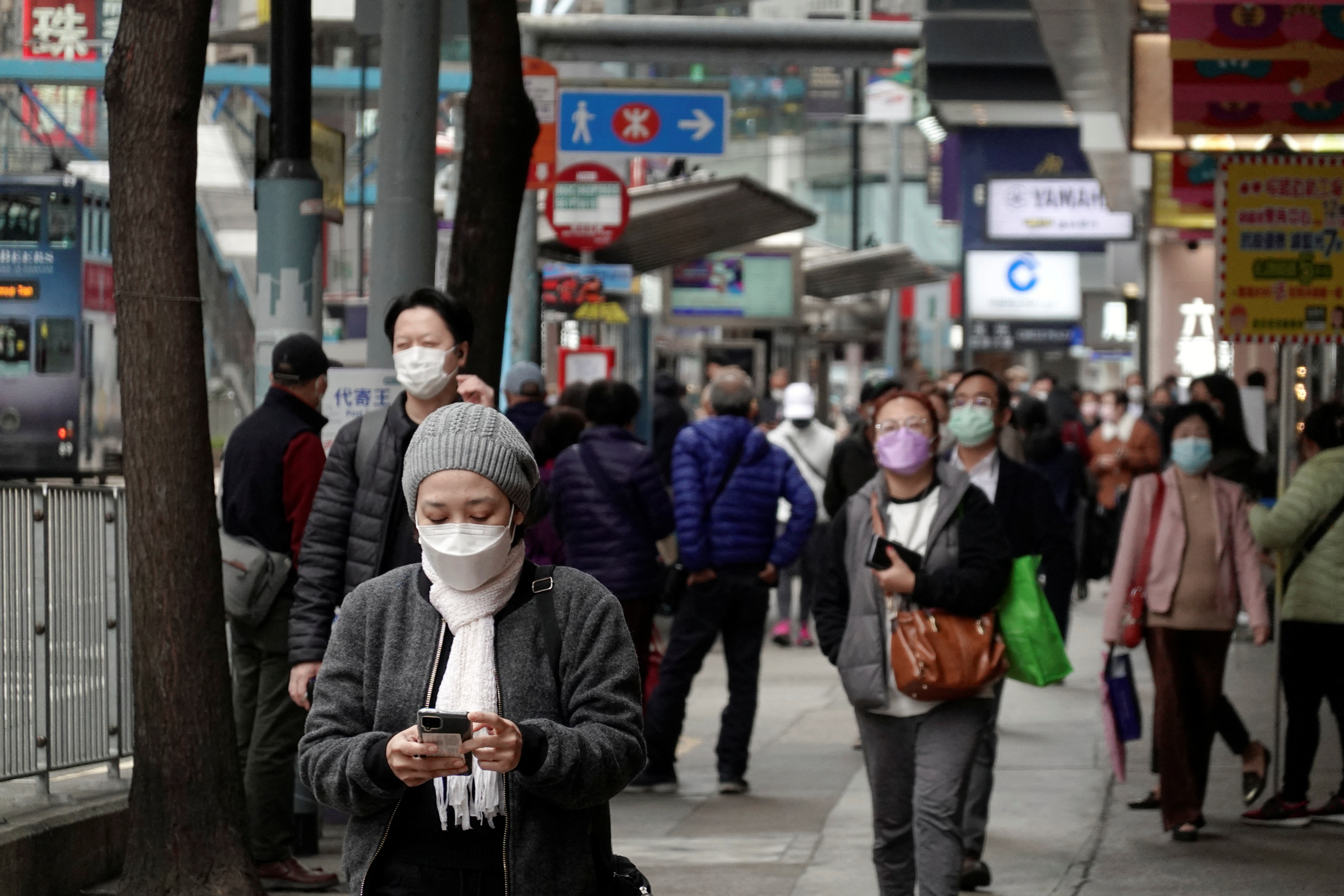 Pedestrians wearing face masks walk on a street in Hong Kong