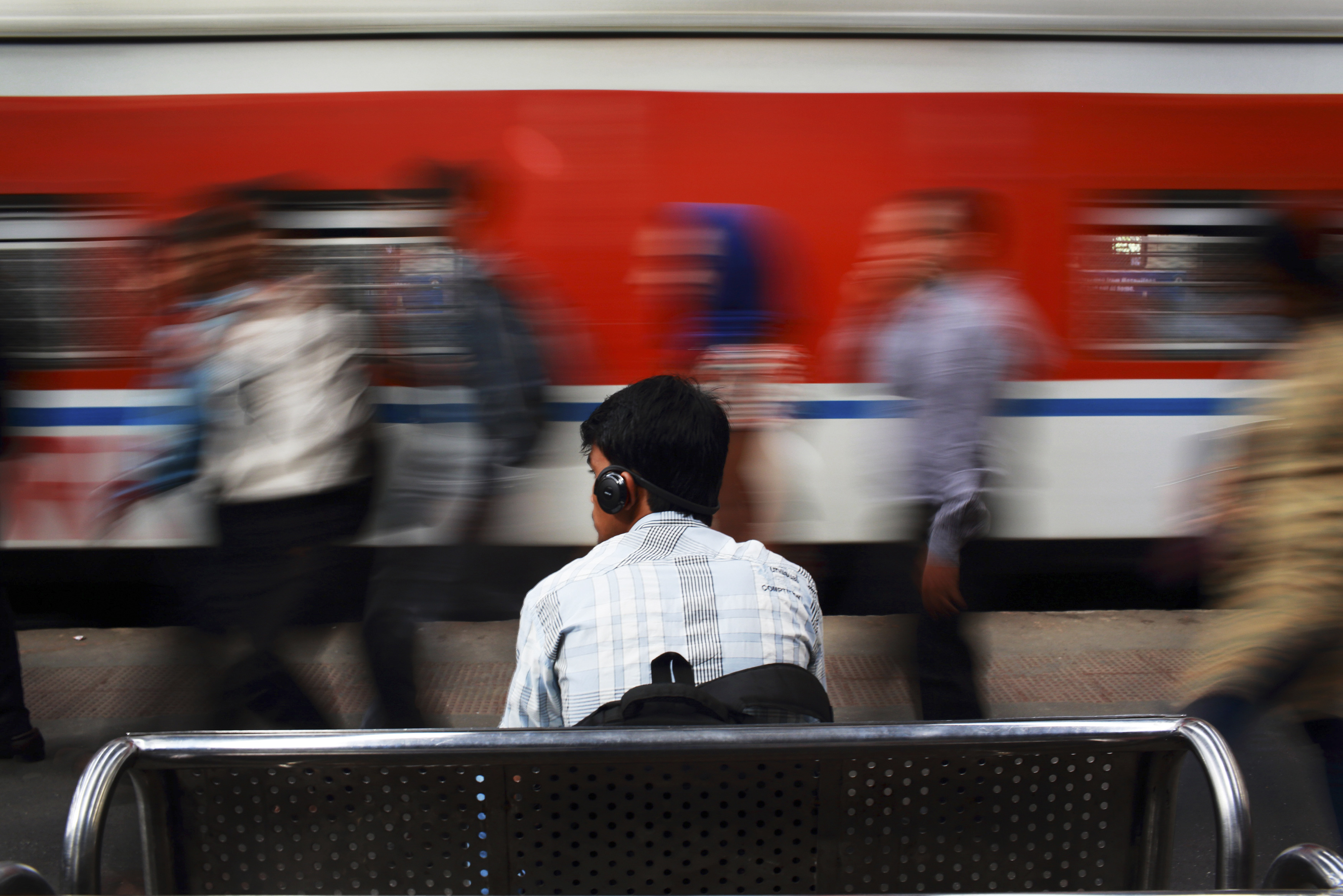 A man listens to music as he waits for his train at Churchgate railway station in Mumbai