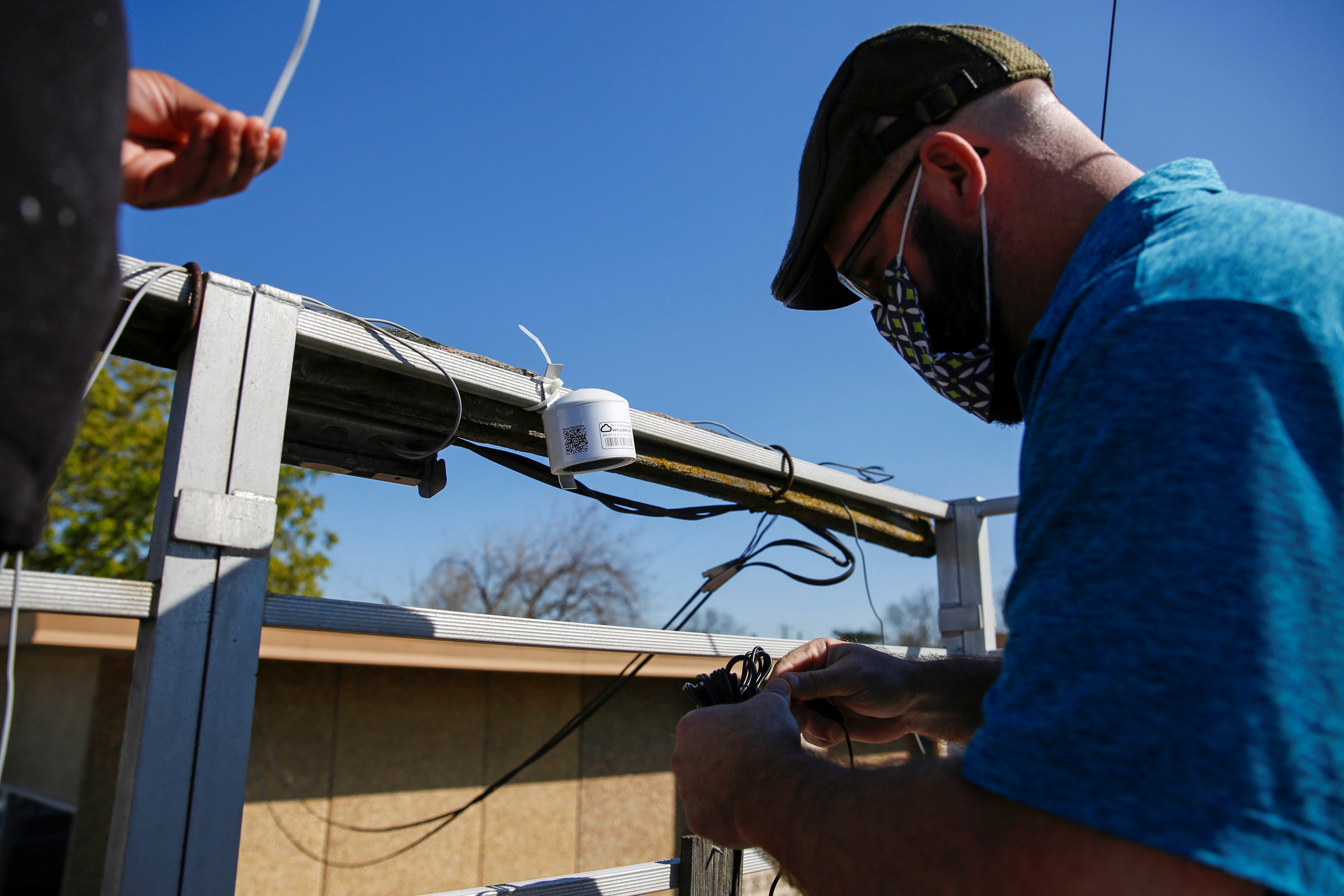 Matt Holmes, a community engagement specialist with Little Manila Rising, installs a low-cost remote air sensor by Purple Air at a monitoring station in Stockton, California, U.S., March 12, 2021.  REUTERS/Brittany Hosea-Small