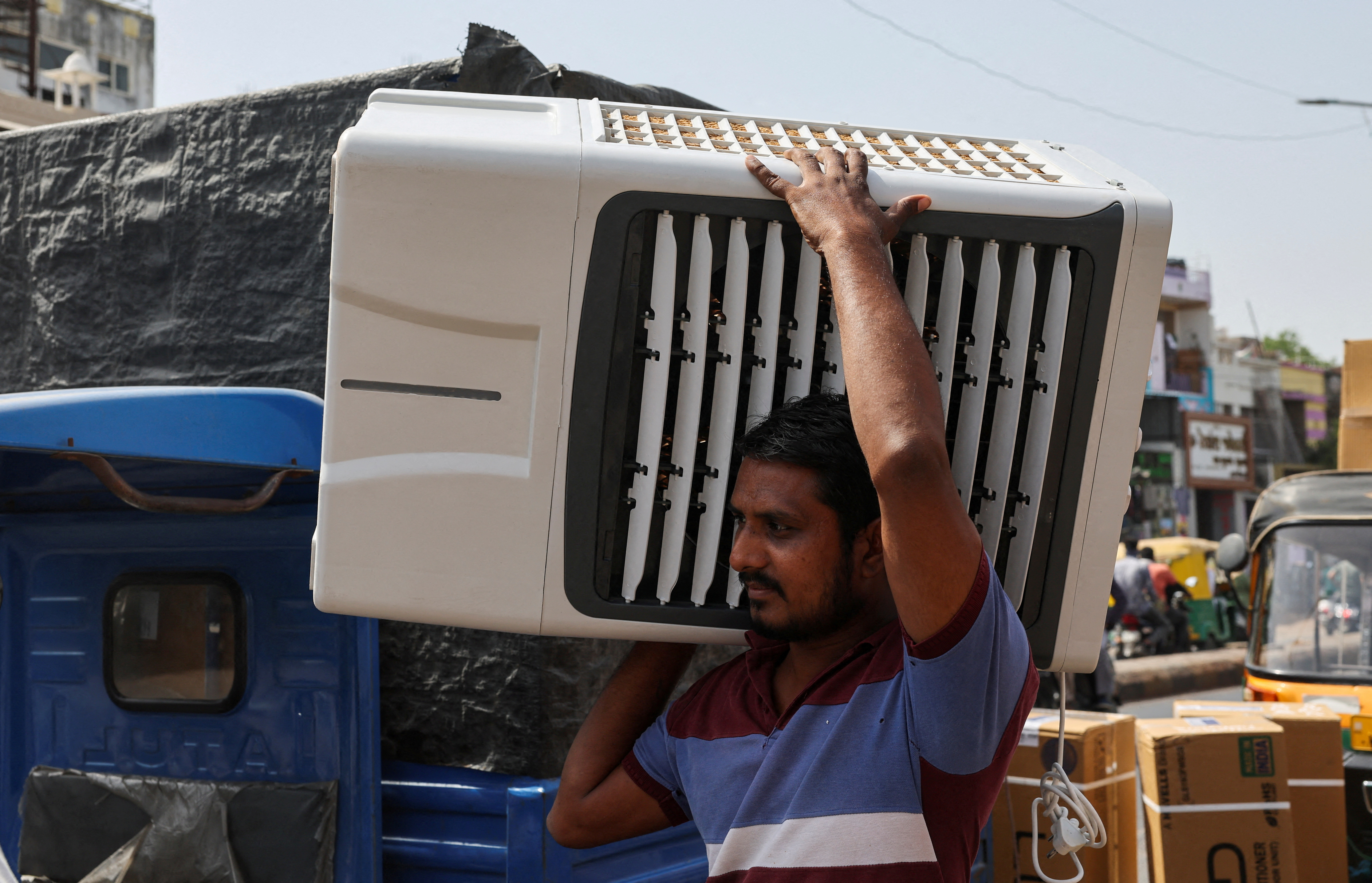 A worker carries an air cooler for delivery to a customer during the heat wave in Ahmedabad