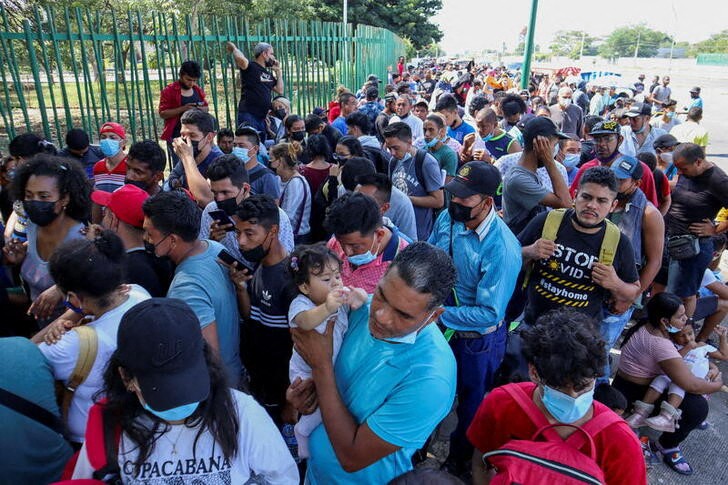 Migrants from Central America line up as they wait for a QR code to register their migratory situation, in Tapachula