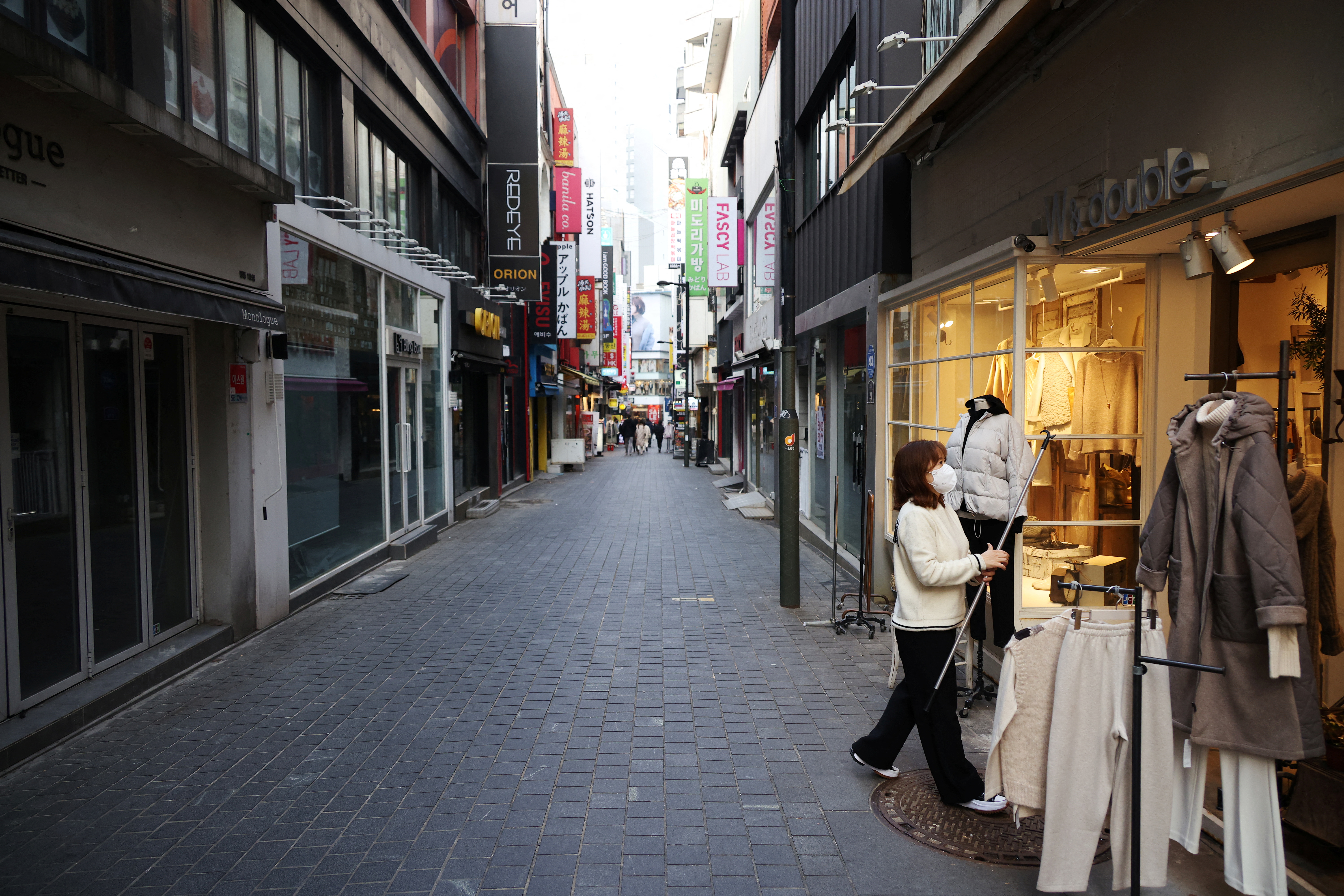 An employee puts up clothing on display amid the COVID-19 pandemic at an empty shopping district in Seoul