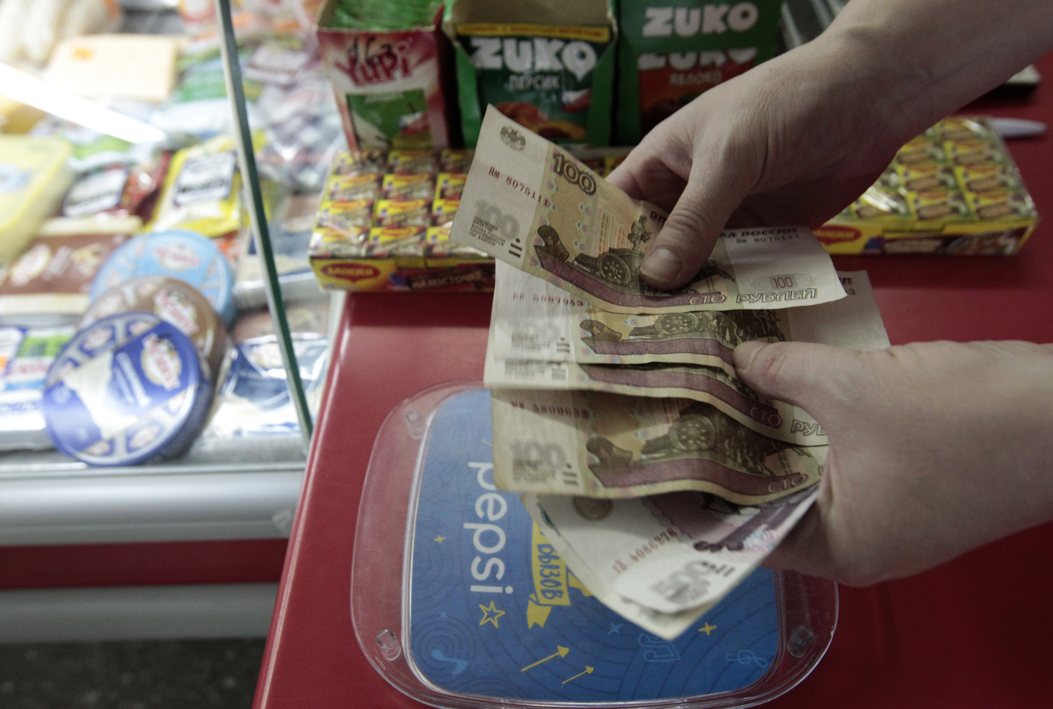 A shop assistant demonstrates Russian rouble banknotes at a grocery in Stavropol