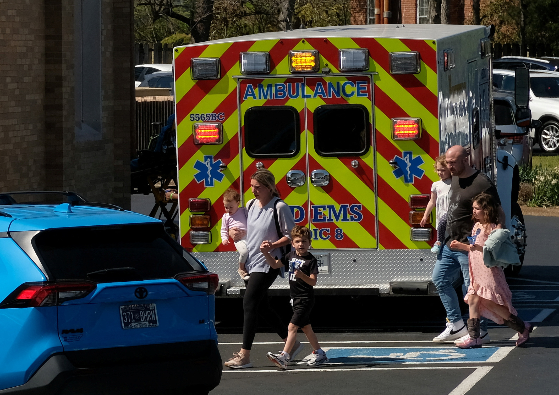 People walk with children beside an emergency vehicle at a family reunification center after a mass shooting at the Covenant School in Nashville