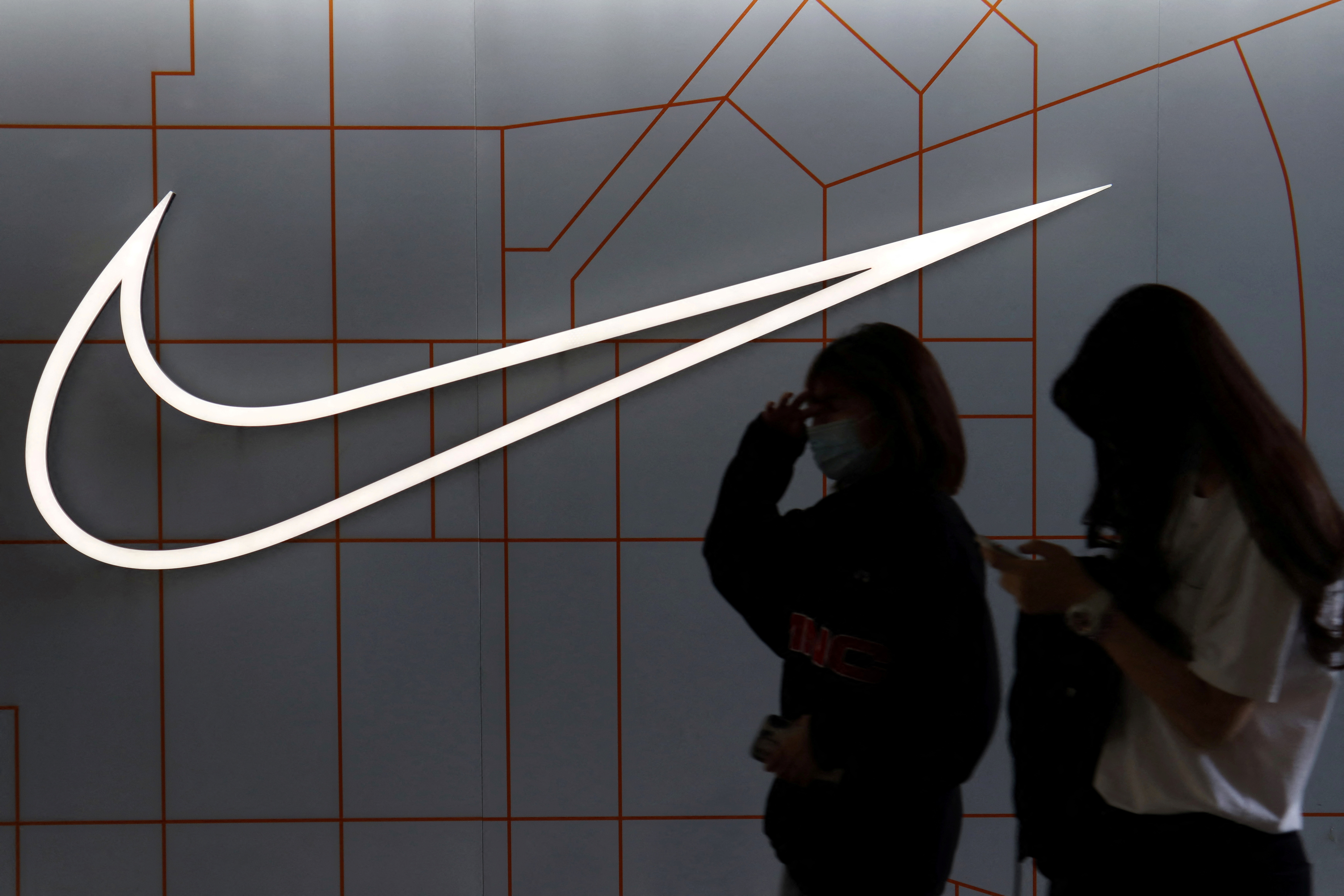 People walk past a Nike Inc store at a shopping complex in Beijing