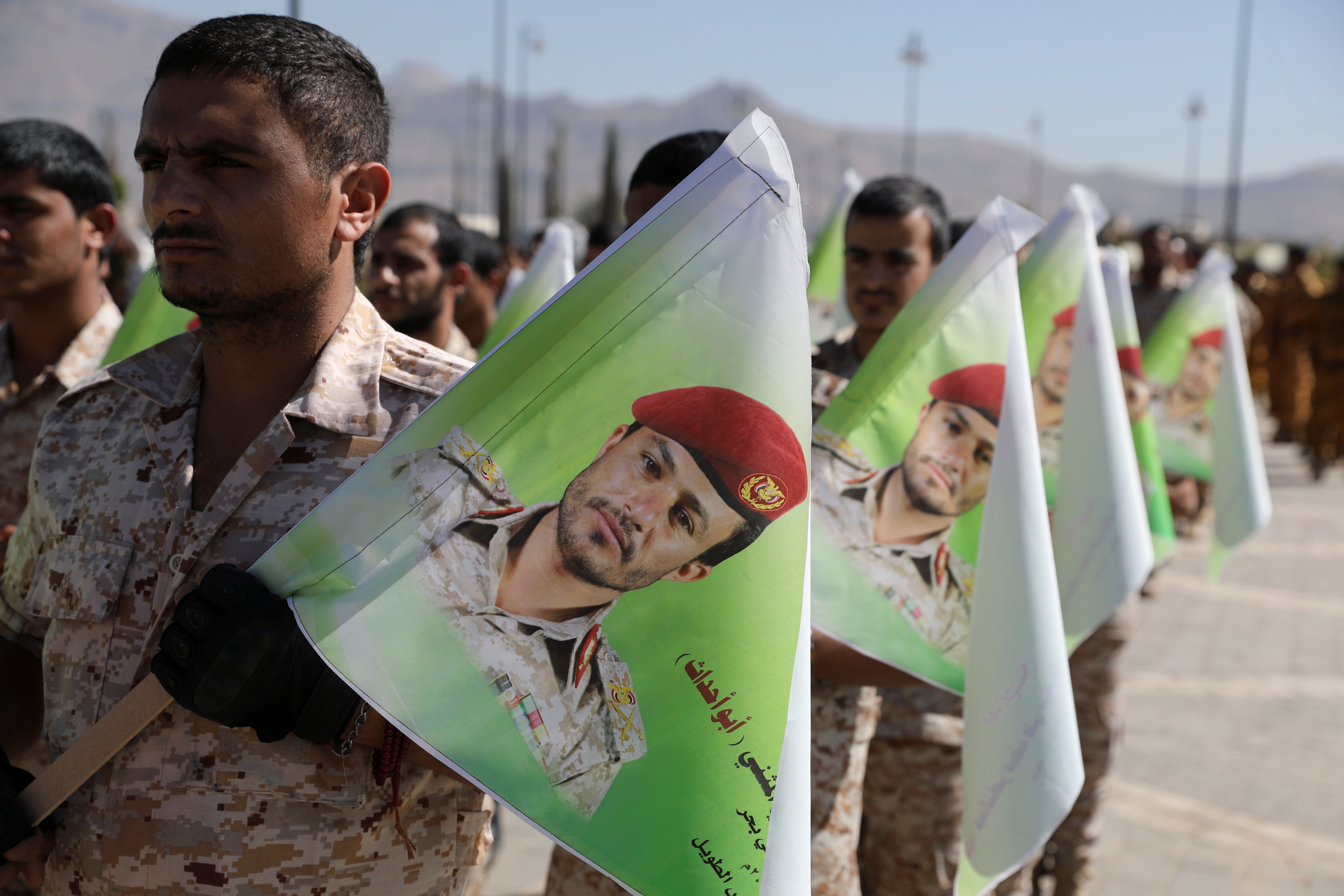 Newly recruited Houthi soldiers hold flags depicting a Houthi commander killed in recent fighting against government forces, during his funeral in Sanaa, Yemen December 6, 2021. REUTERS/Khaled Abdullah