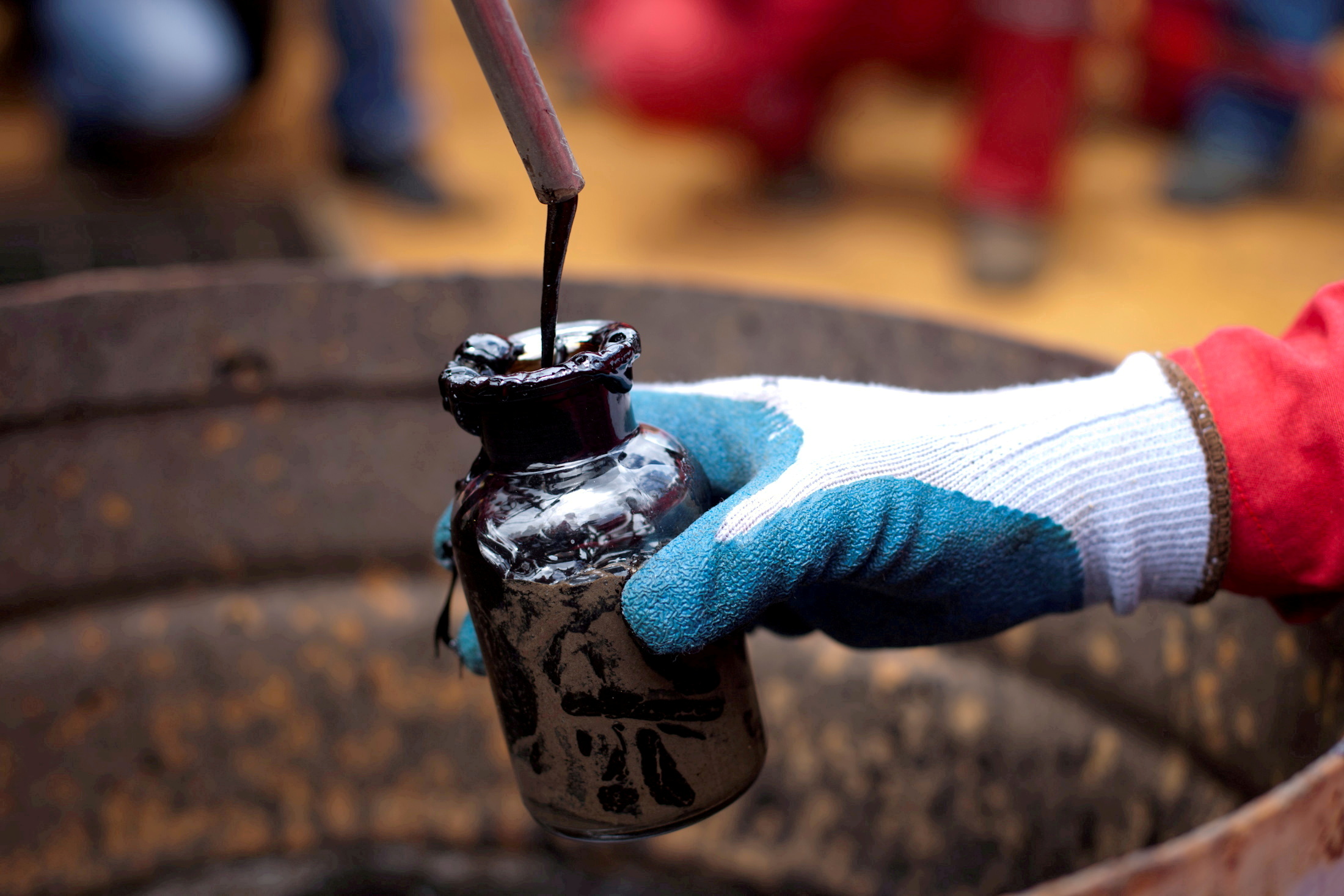 A worker collects a crude oil sample at an oil well operated by Venezuela's state oil company PDVSA in Morichal