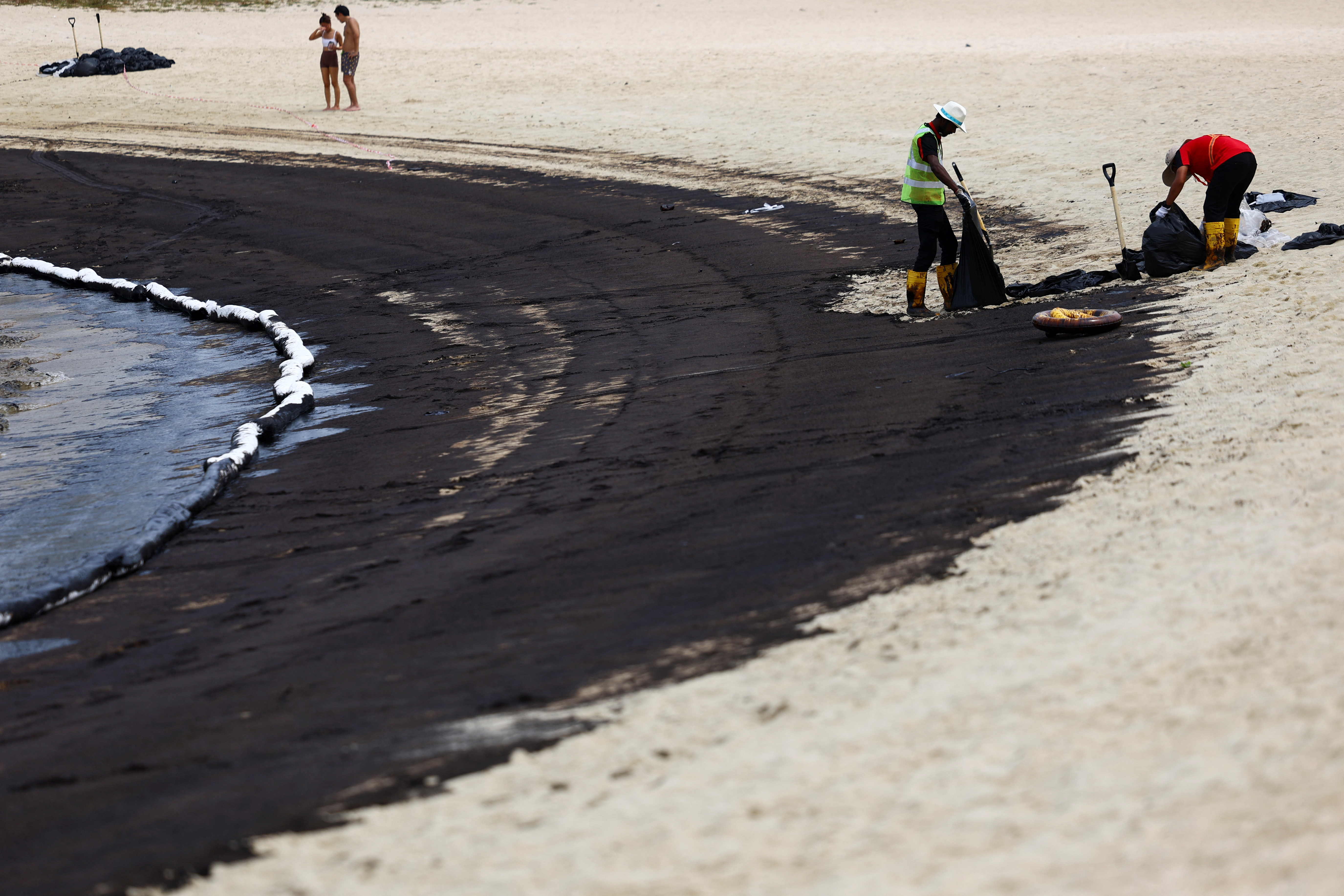 Workers clean up the beach following an oil slick at Tanjong Beach in Sentosa, Singapore