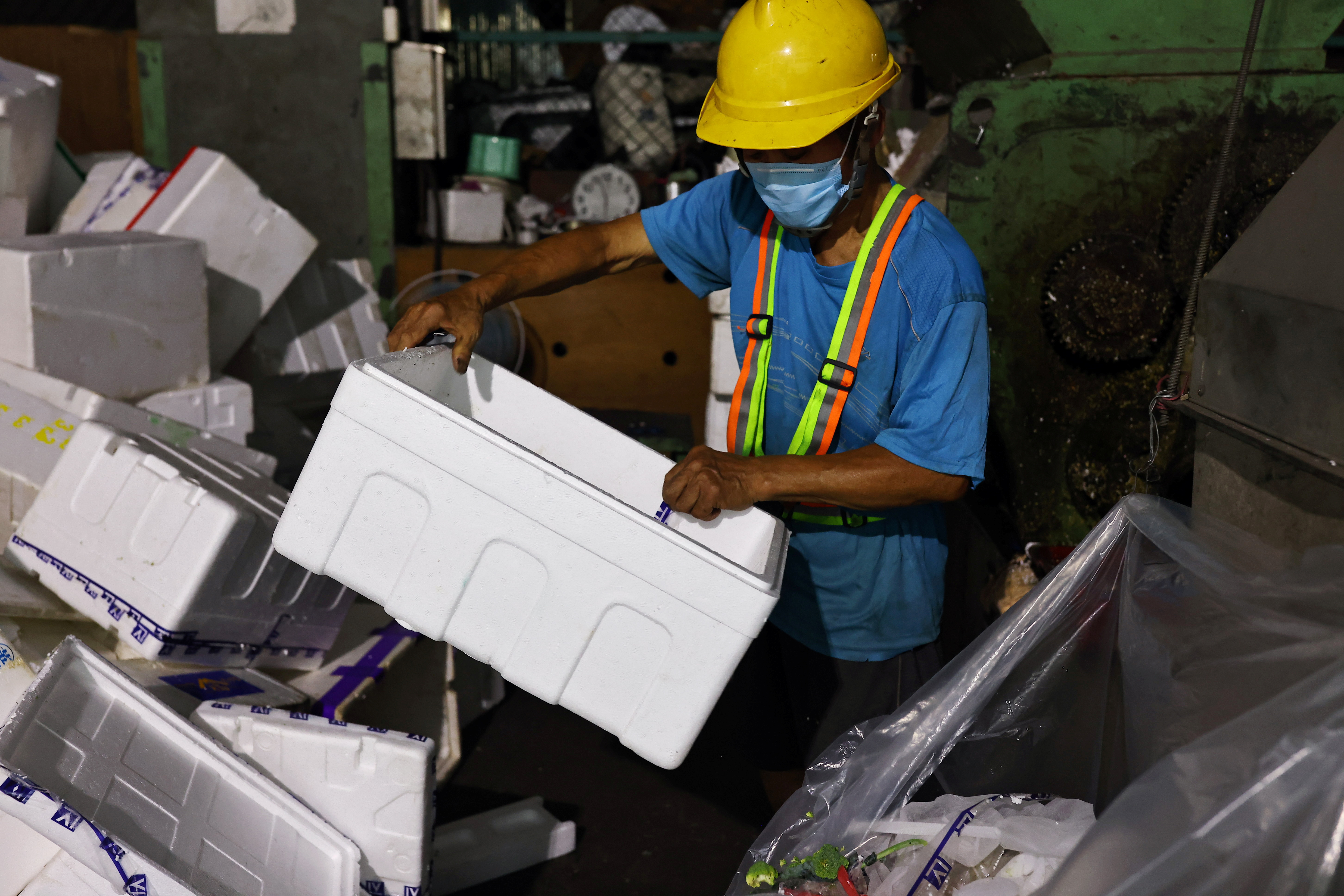 Staff member prepares styrofoam boxes to be melted at a waste collection plant in Taipei