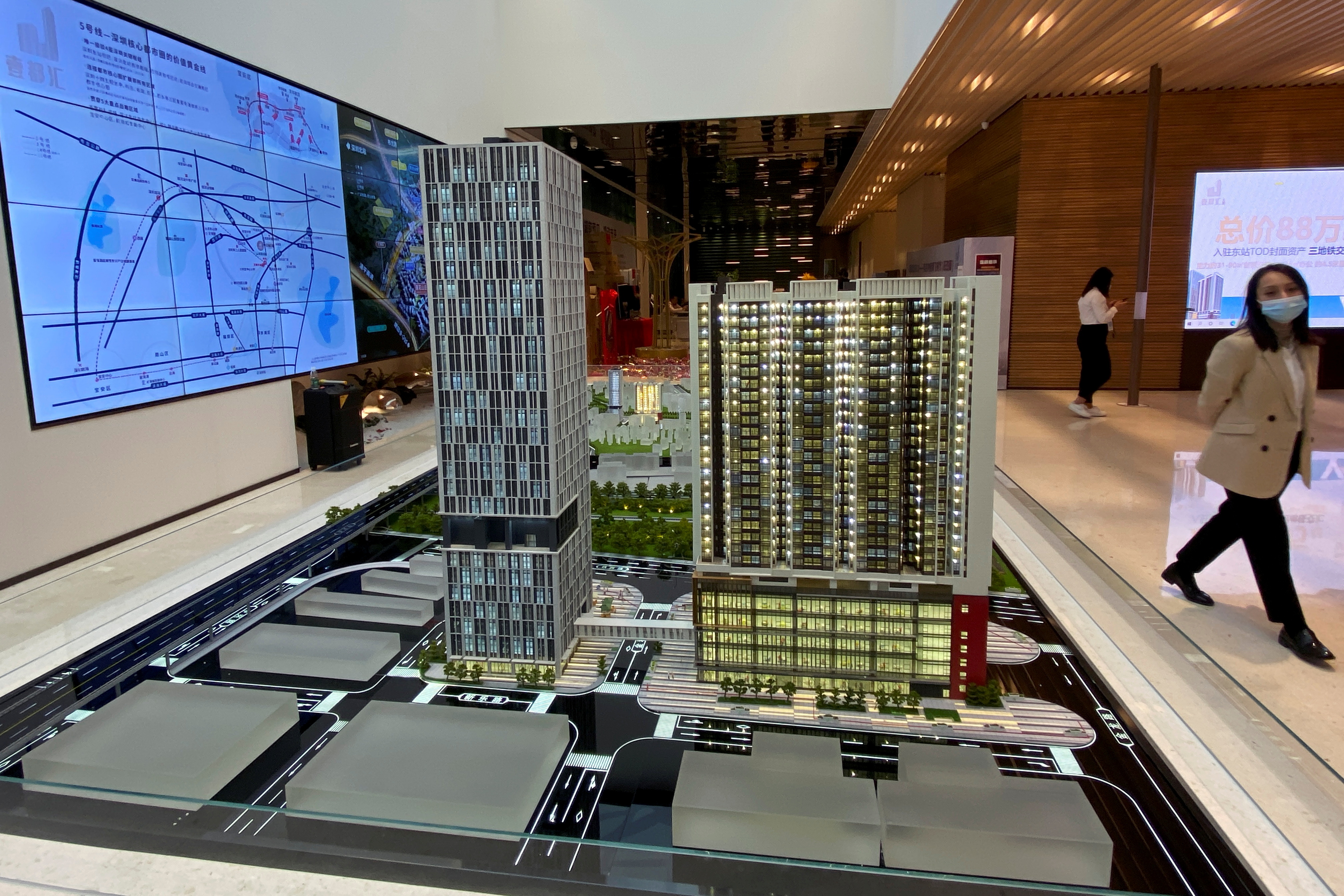 Woman walks past a property model at a sales office of Kaisa Group Holdings Ltd in Shenzhen