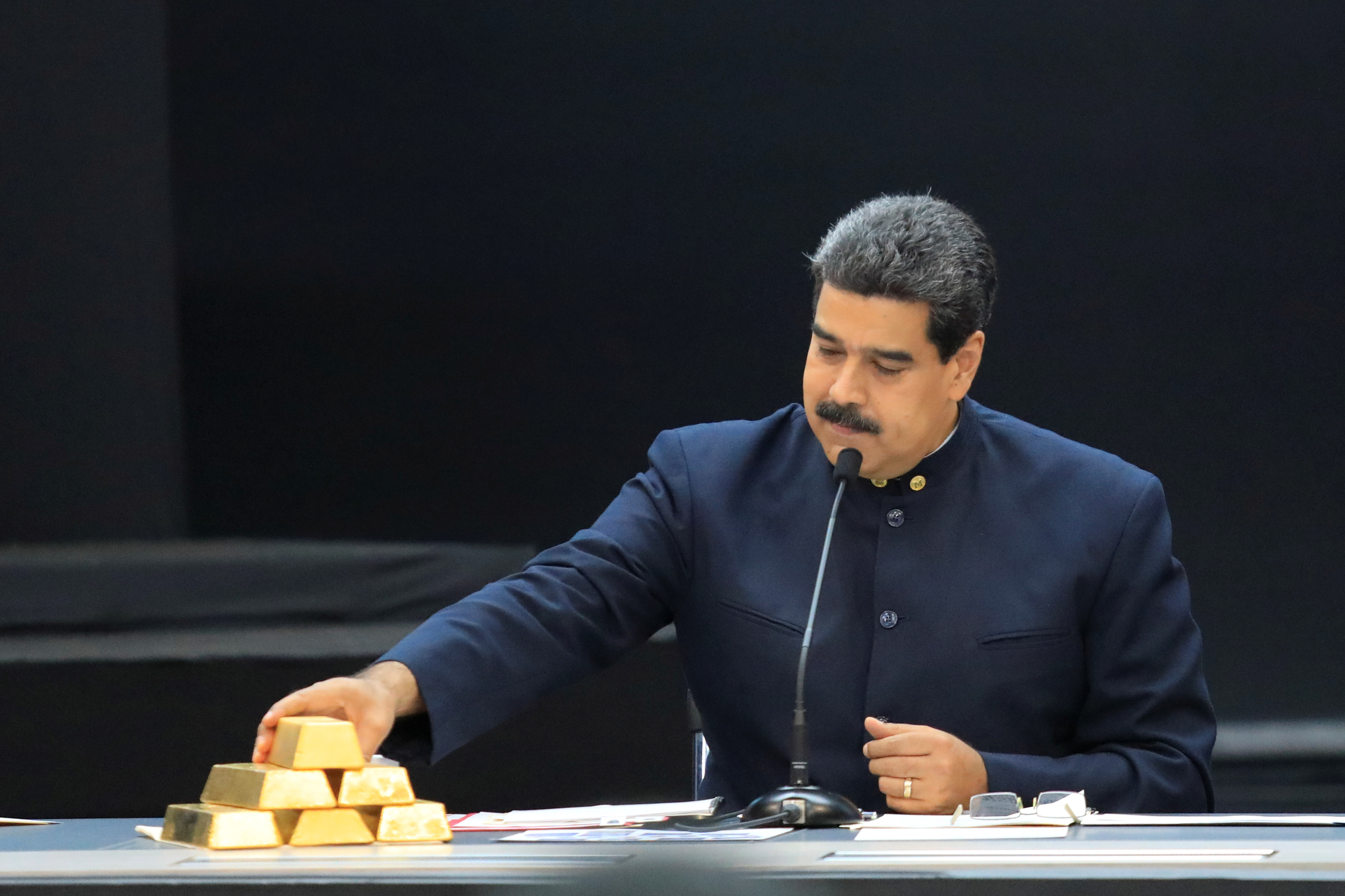 Venezuela's President Maduro touches a gold bar as he speaks during a meeting with the ministers responsible for the economic sector in Caracas