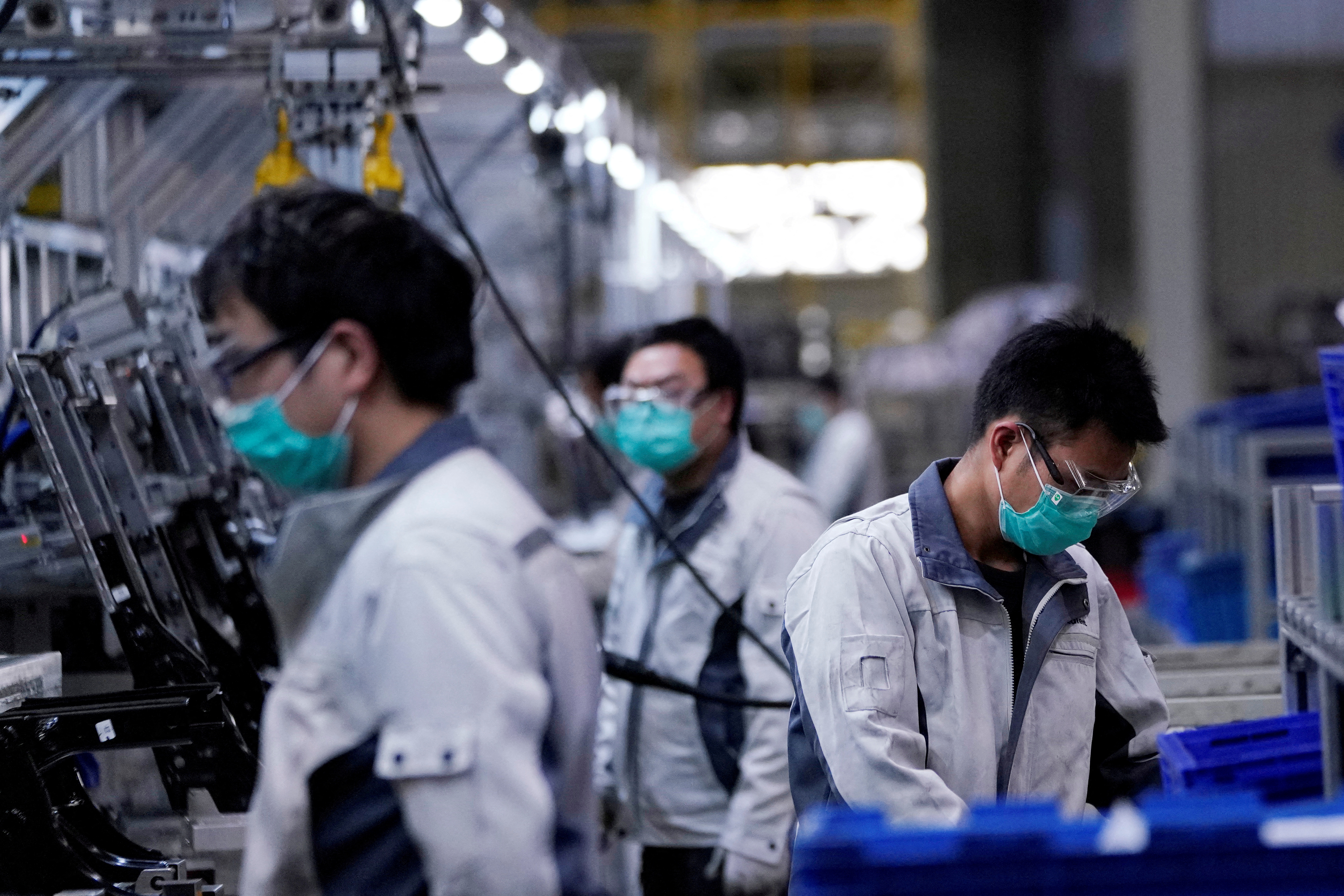 FILE PHOTO: Employees wearing face masks work on a car seat assembly line at Yanfeng Adient factory in Shanghai