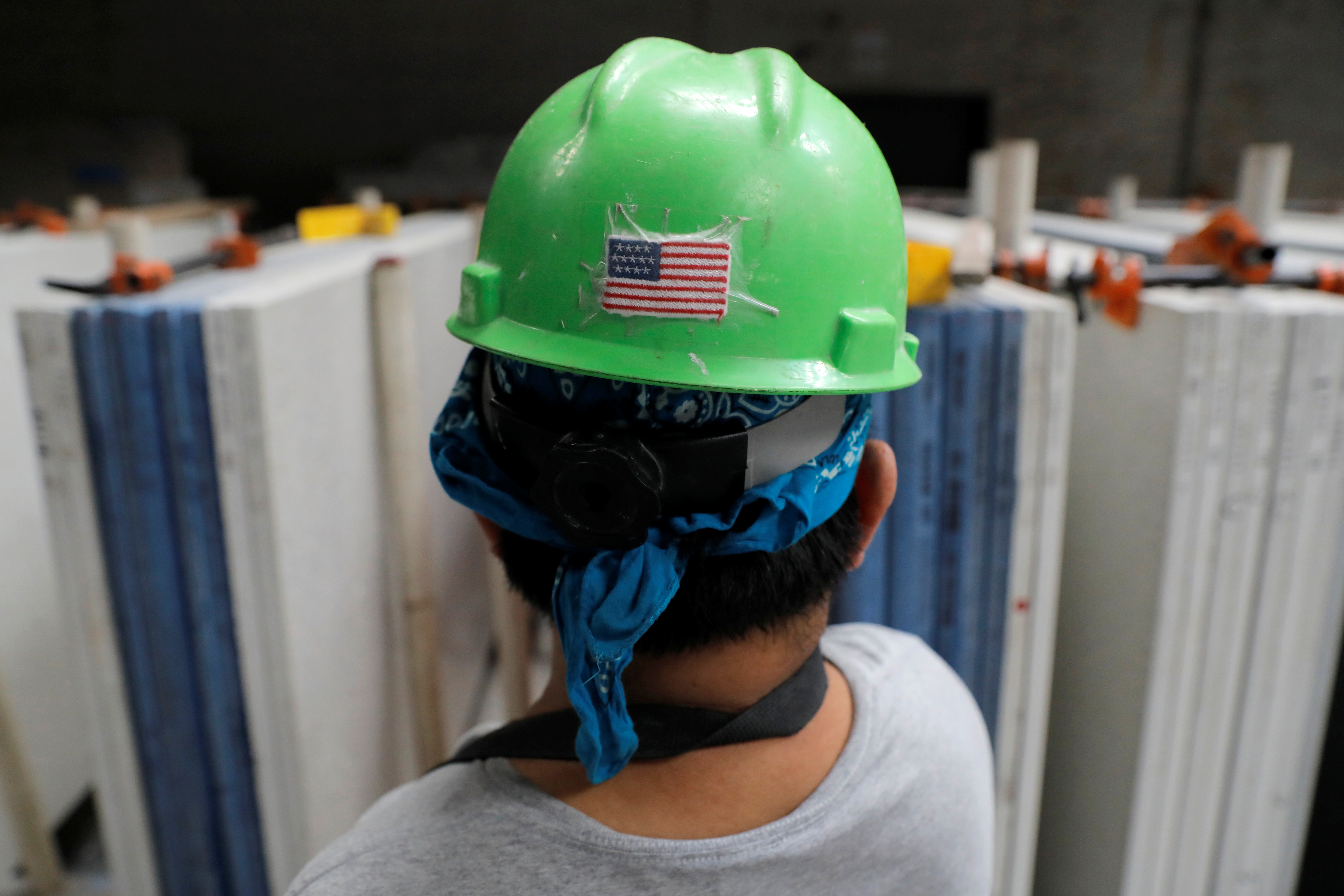 A U.S. flag is seen on the hard hat of a worker in the factory at IceStone, a manufacturer of recycled glass countertops and surfaces, in New York City, New York