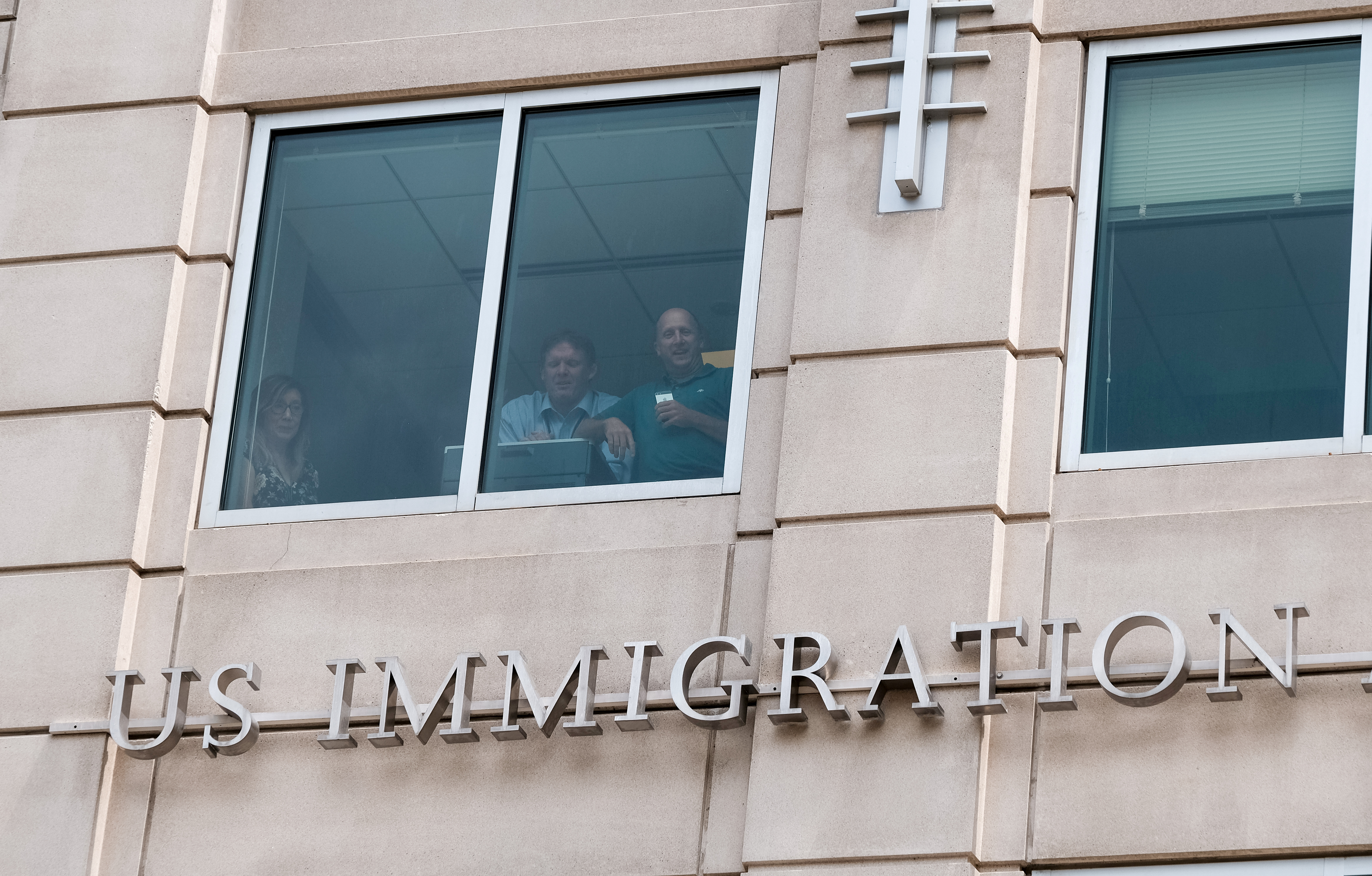 U.S. Immigration and Customs Enforcement employees watch from a window as activists hold the 