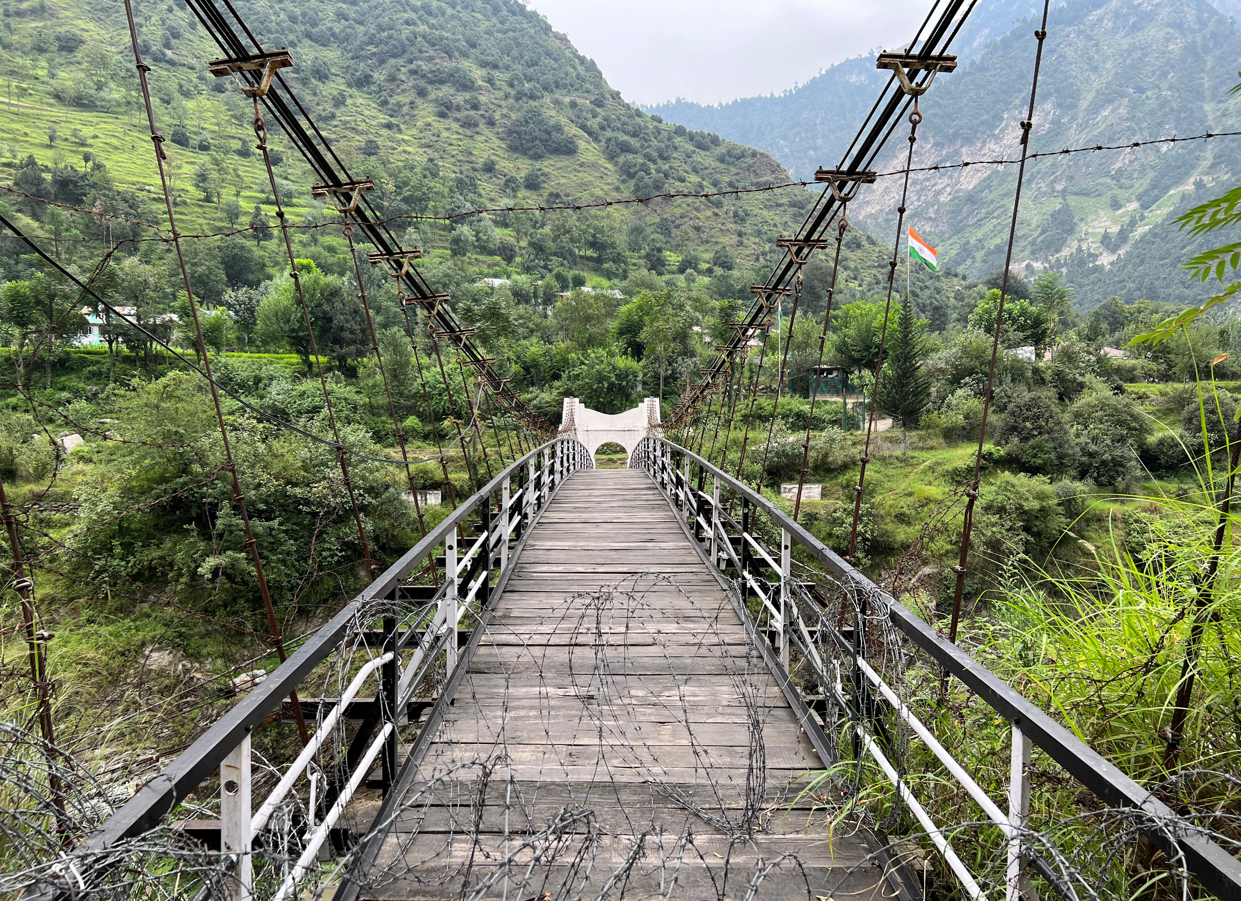 A general view of a bridge between Pakistan and India, closed since 2018, with an Indian flag in the background, in Chilehana