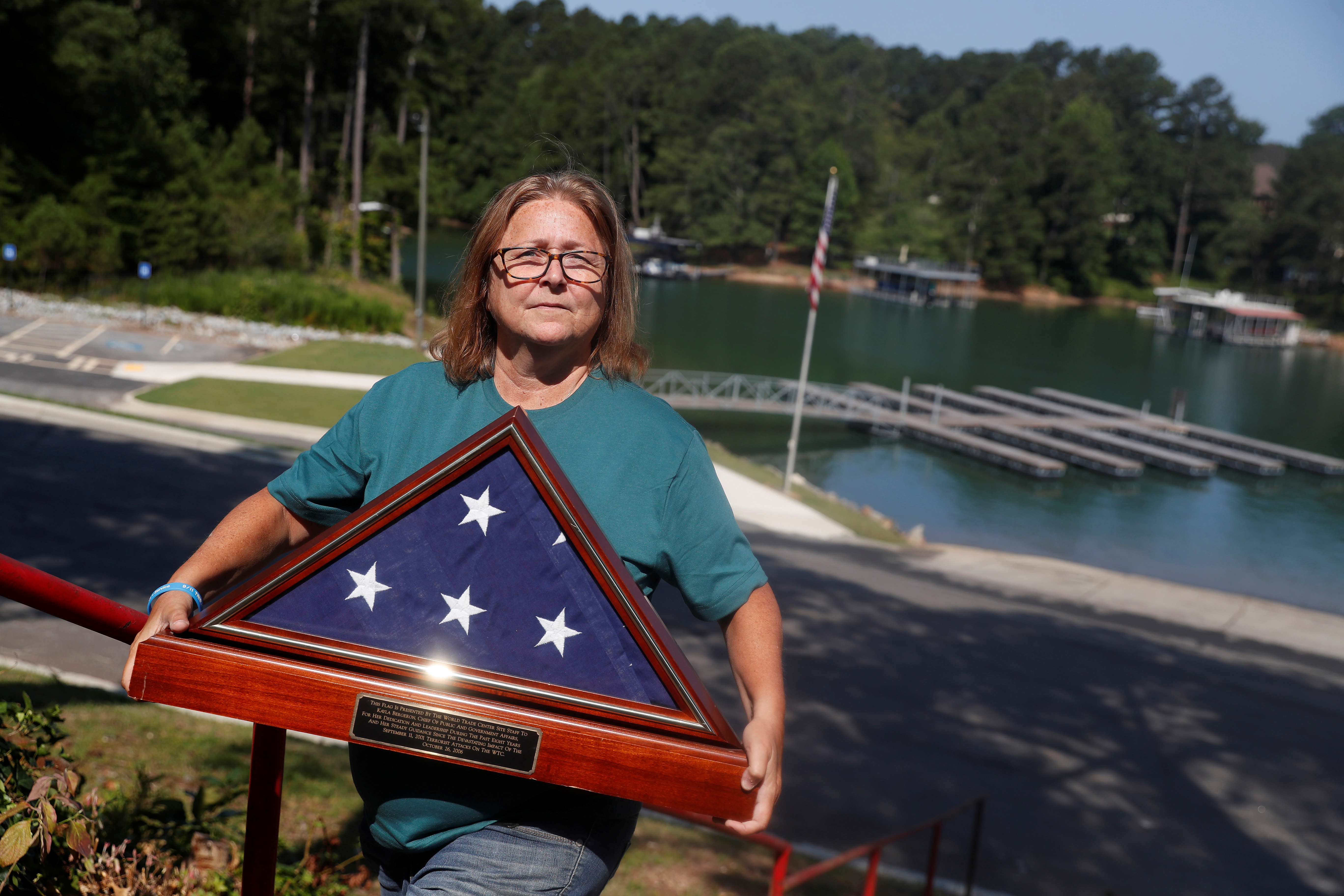 Kayla Bergeron poses with a framed U.S. flag given to her by the agency when she left in 2006 at Lake Lanier in Cumming, Georgia, July 4, 2021. REUTERS/Shannon Stapleton   
