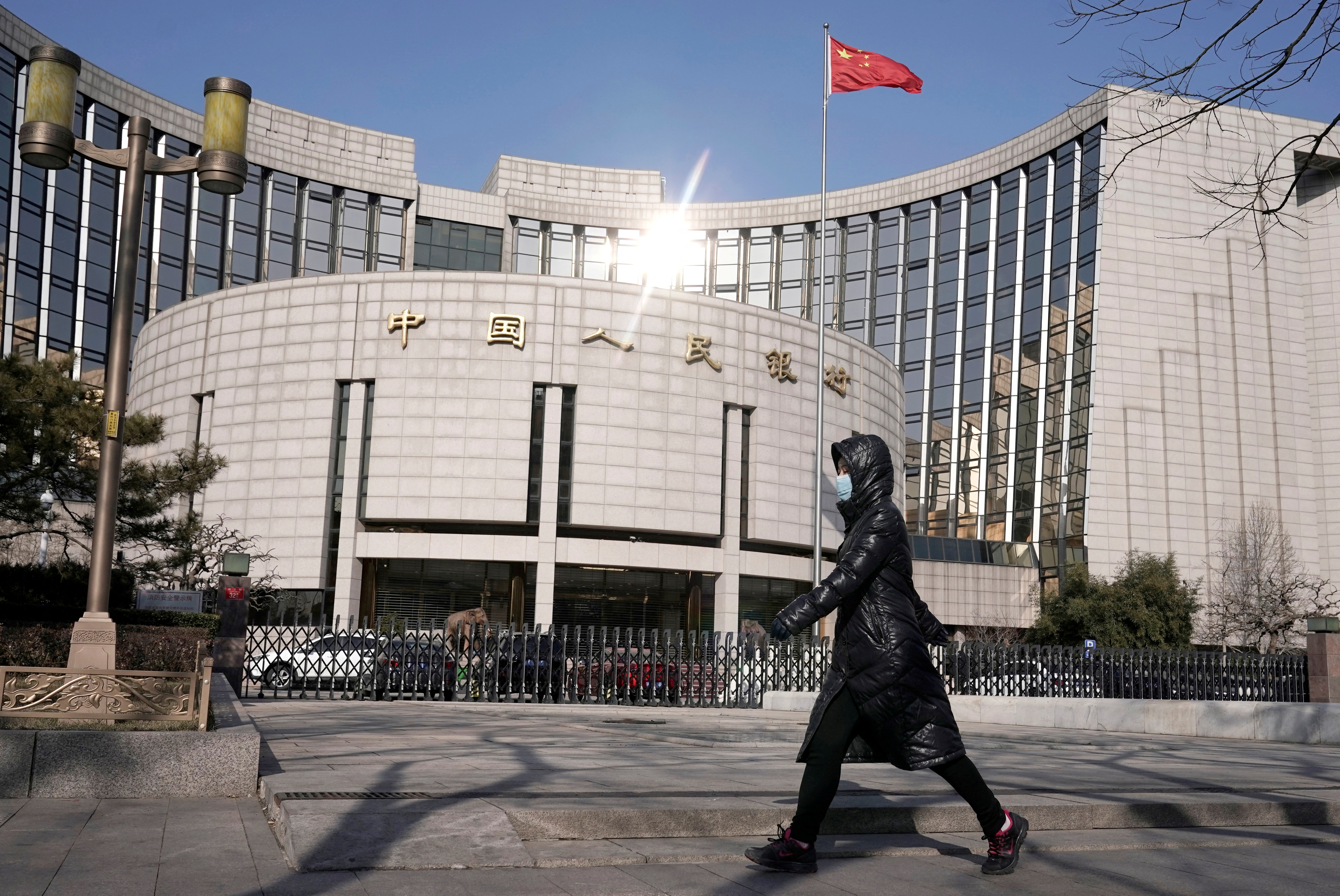 A woman walks past the headquarters of the People's Bank of China, the central bank, in Beijing