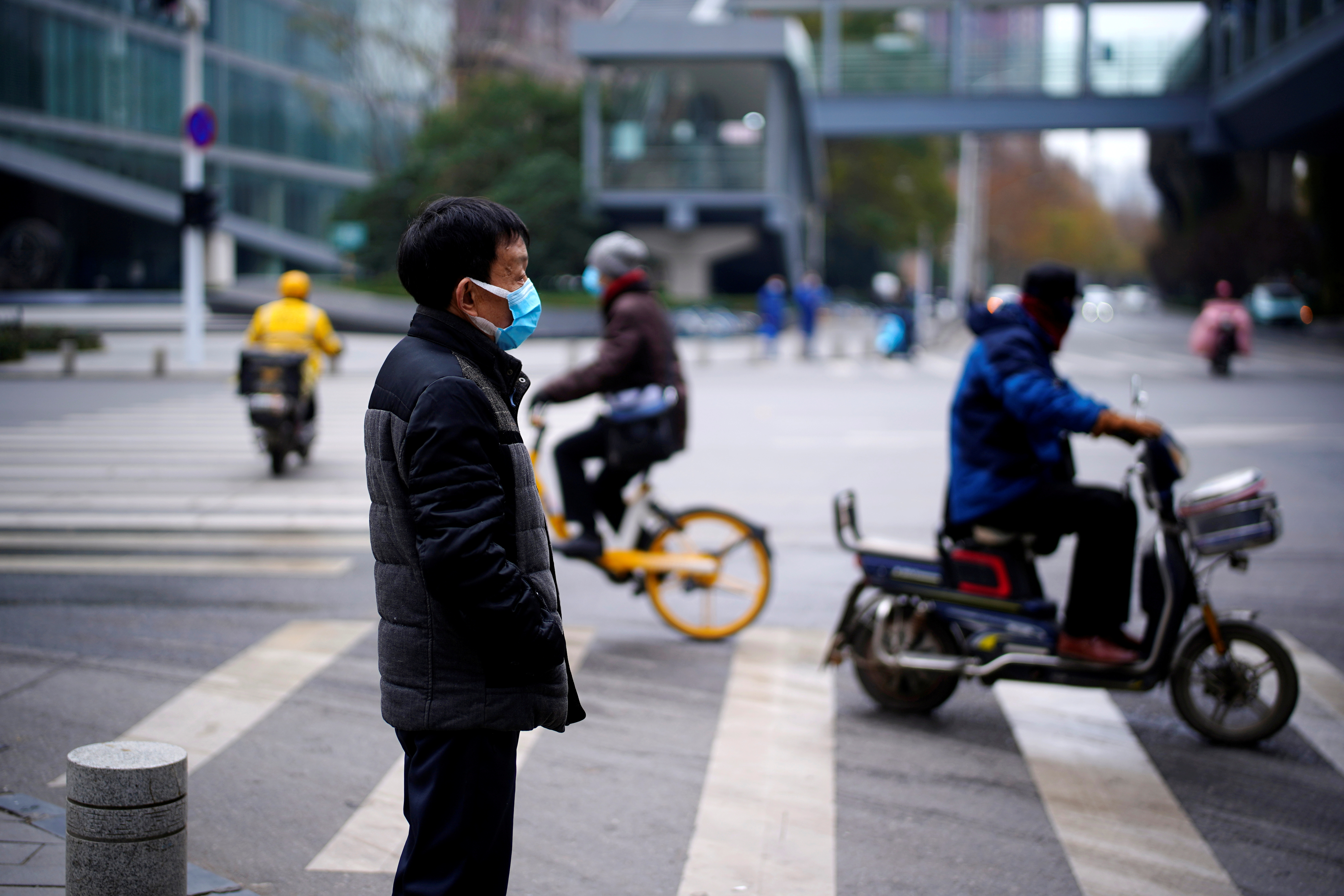 Man wearing a mask stands near a street, almost a year after the start of the coronavirus disease (COVID-19) outbreak, in Wuhan, Hubei