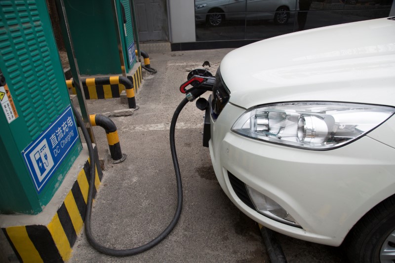 Charging cable is seen hooked to a car at a charging point for electric vehicles in Beijing