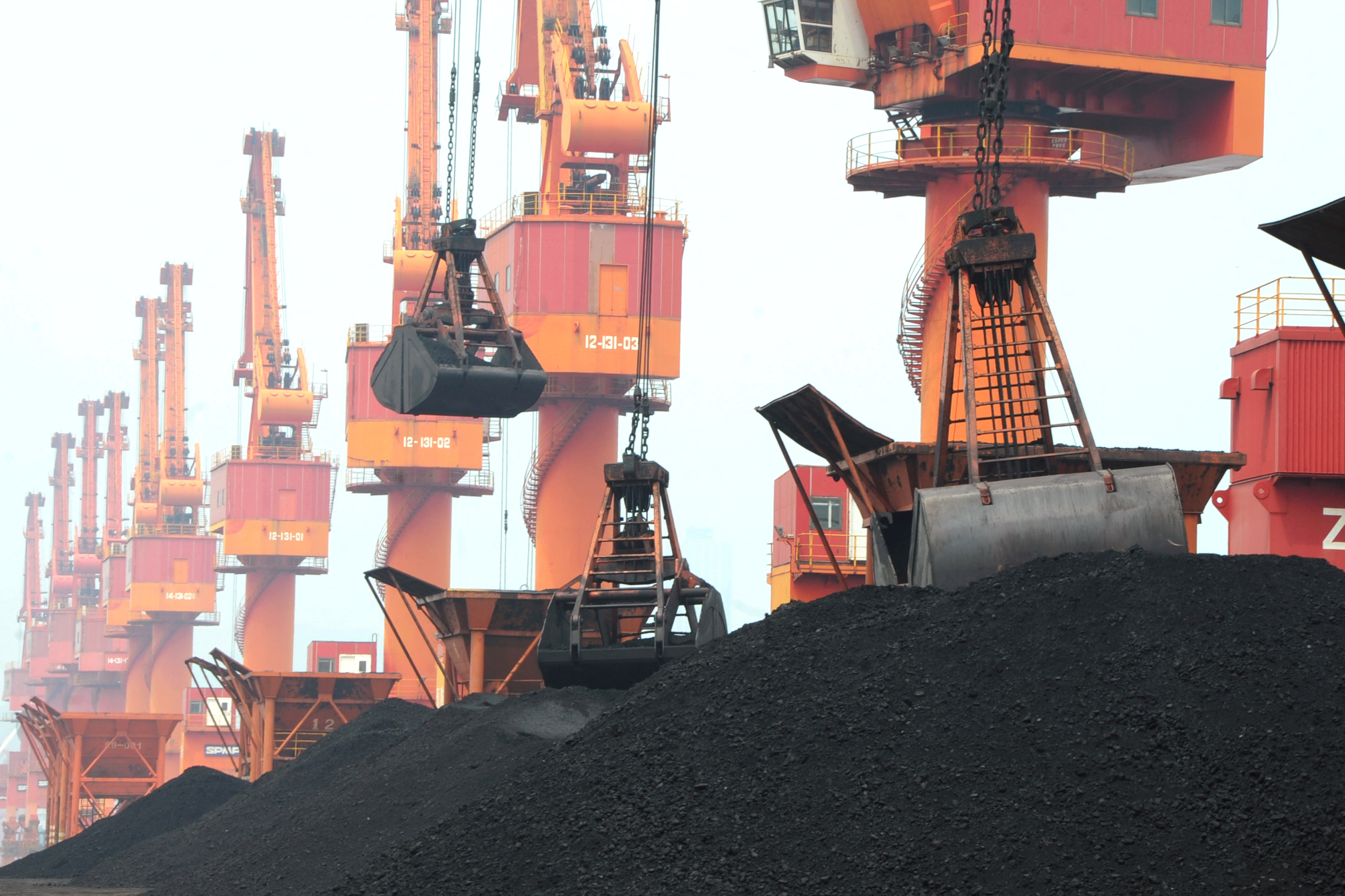Imported coal is seen lifted by cranes from a coal cargo ship at a port in Lianyungang, Jiangsu