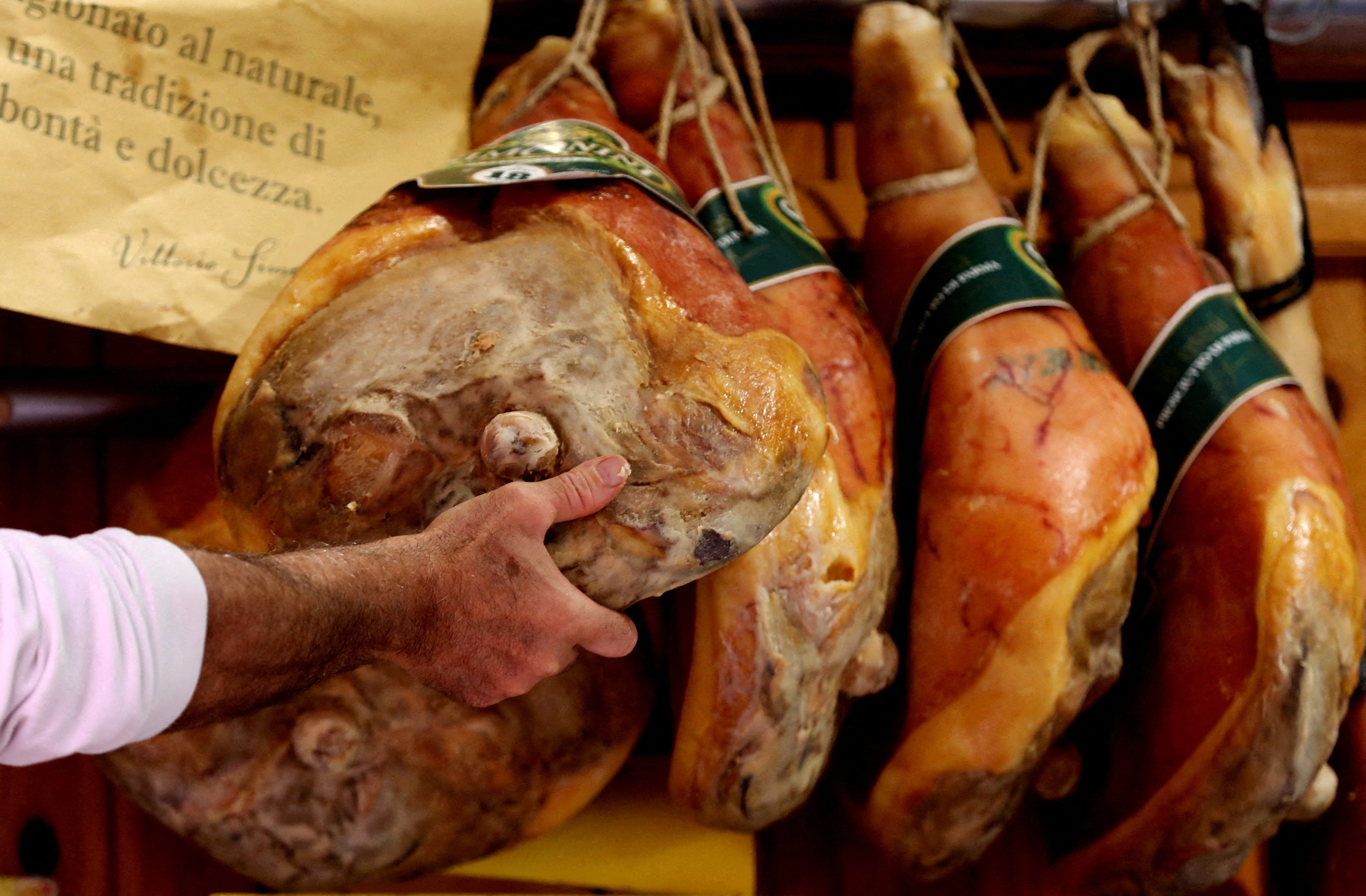 A grocer prepares prosciutto ham in a deli in Rome