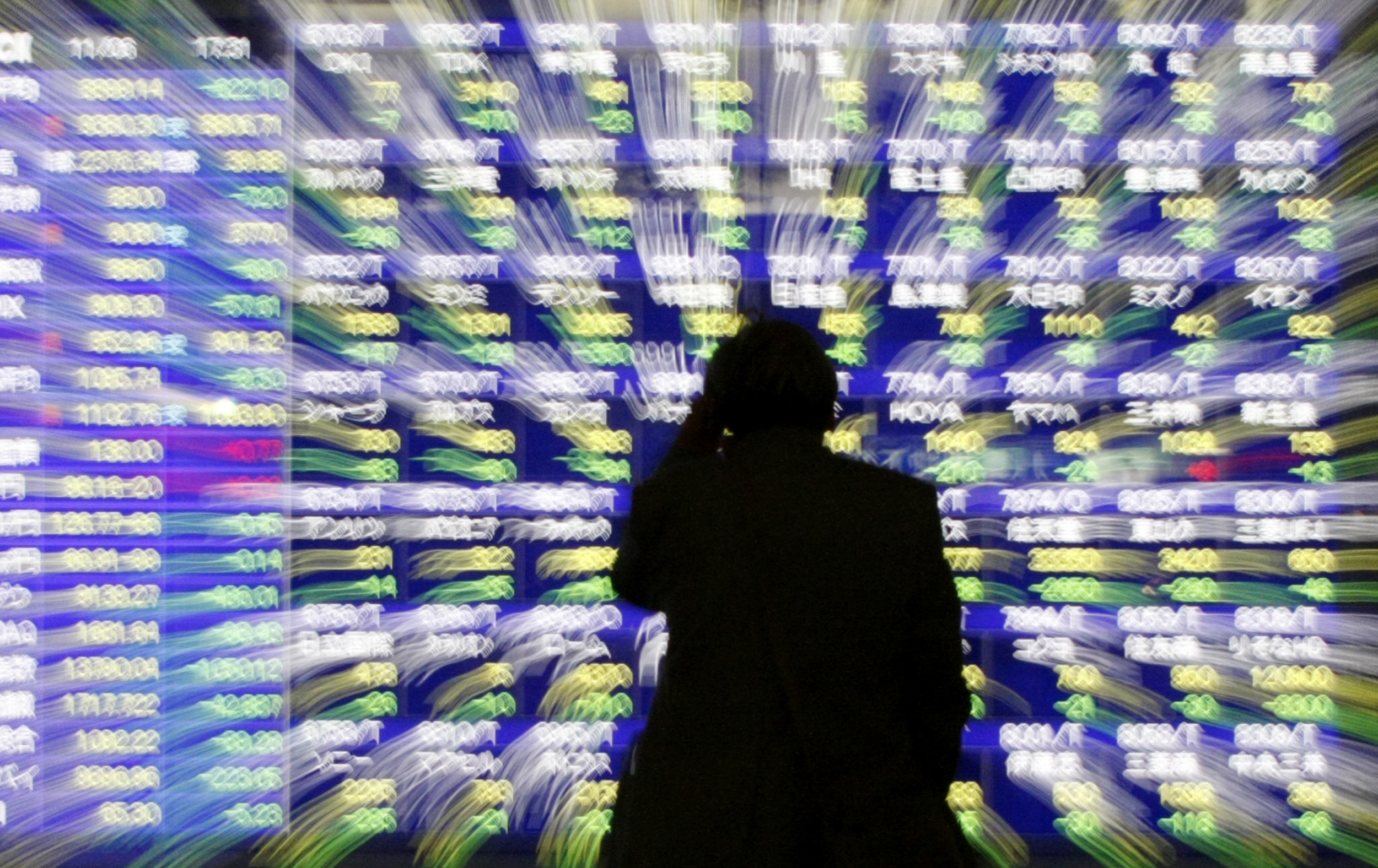 Man looks at a stock quotation board outside a brokerage in Tokyo