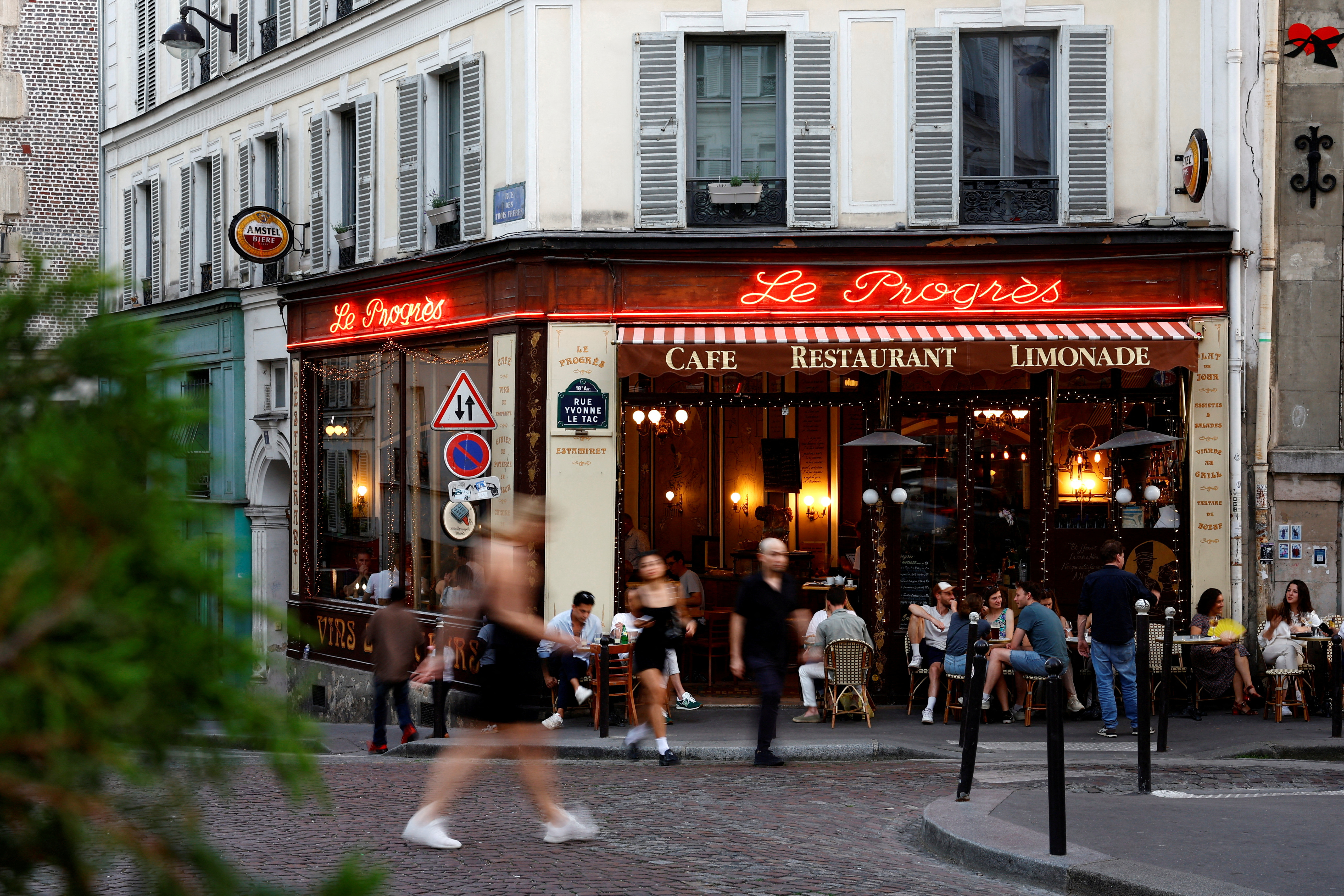 People walk past a restaurant in Paris