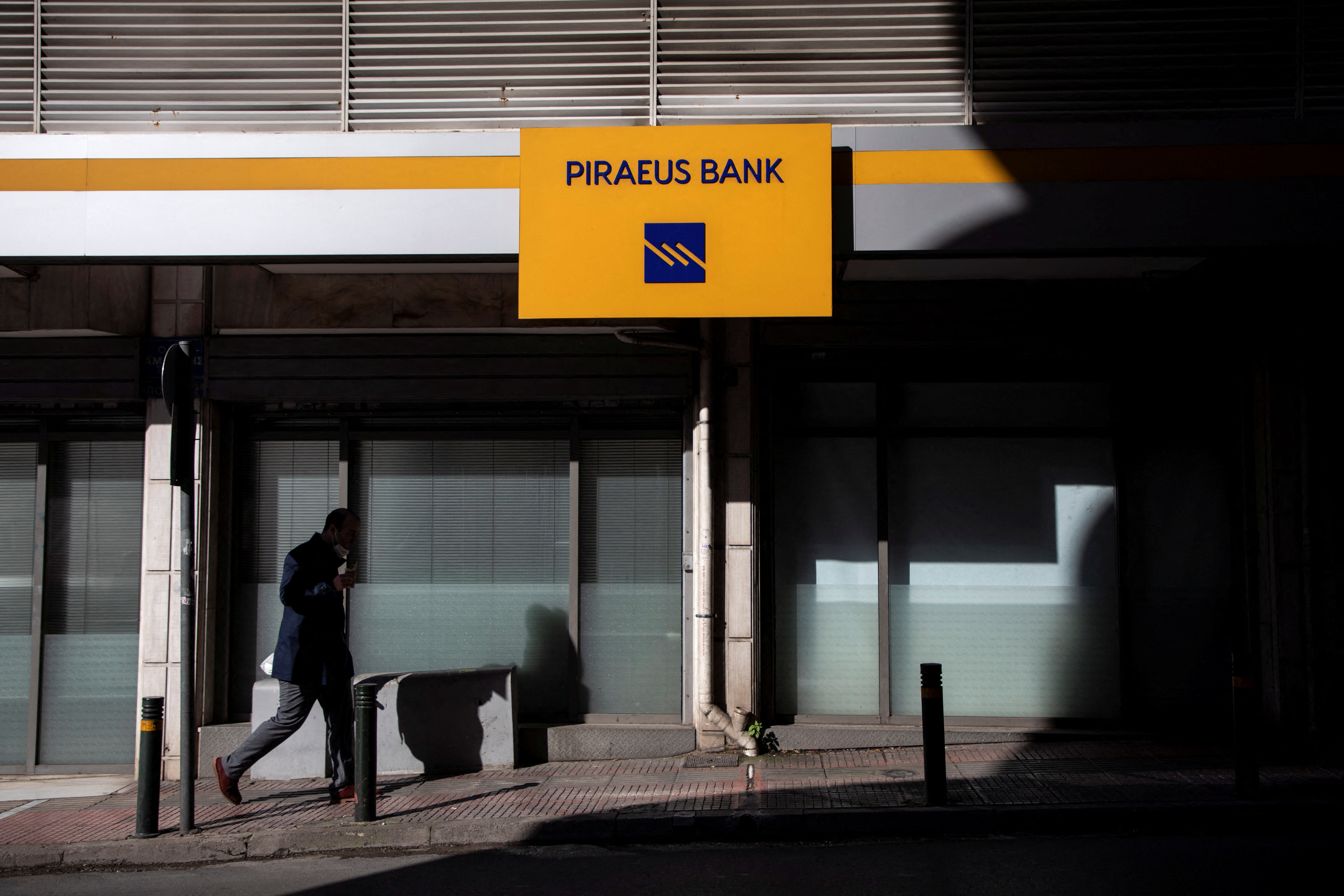 A man walks past a Piraeus Bank branch in Athens