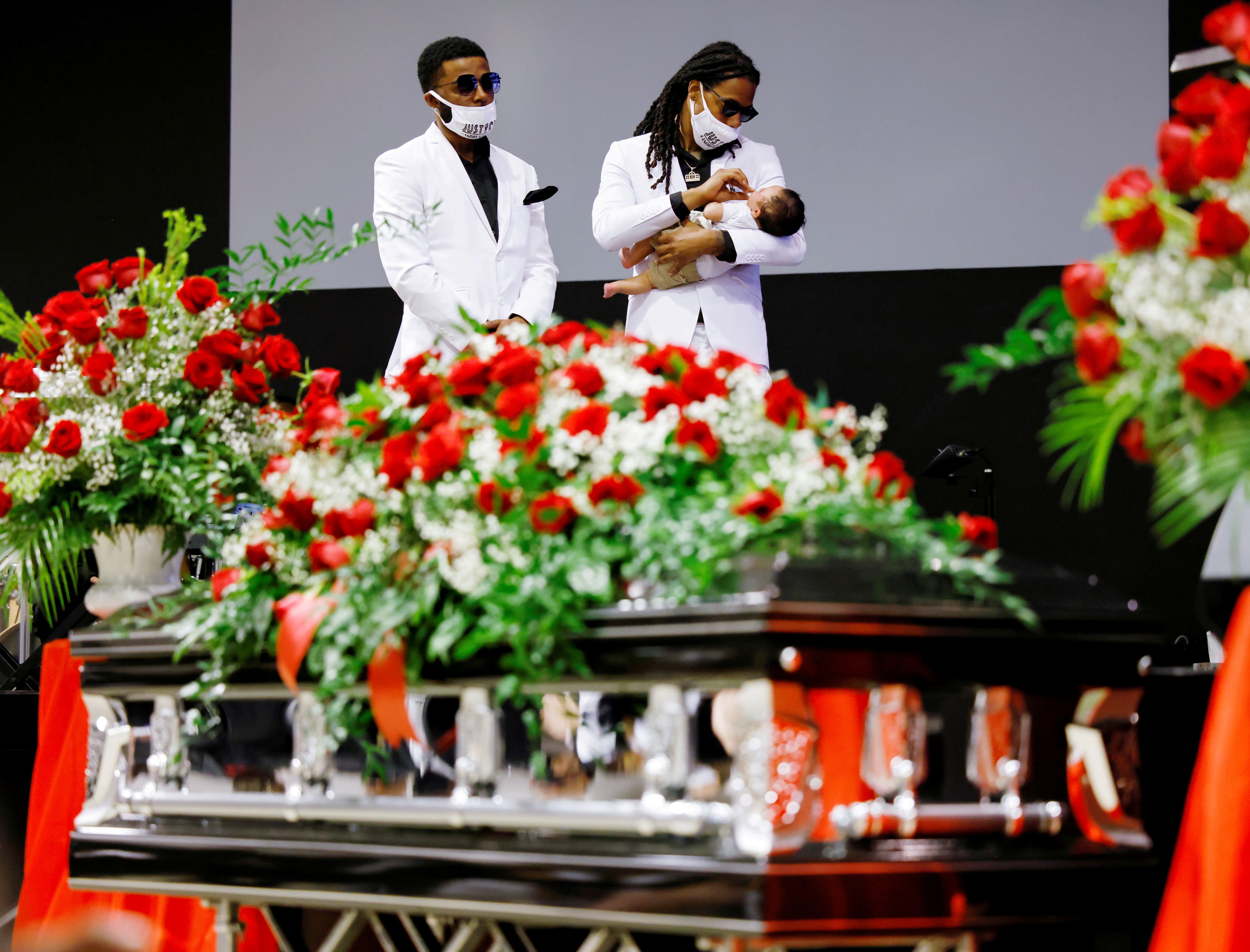Khalil Ferebee tends to his baby son Karter while standing with his brother Jha'rod Ferebee on a stage behind the coffin of their father Andrew Brown Jr. at the funeral in Elizabeth City, North Carolina, U.S., May 3, 2021. REUTERS/Jonathan Drake     TPX IMAGES OF THE DAY/File Photo