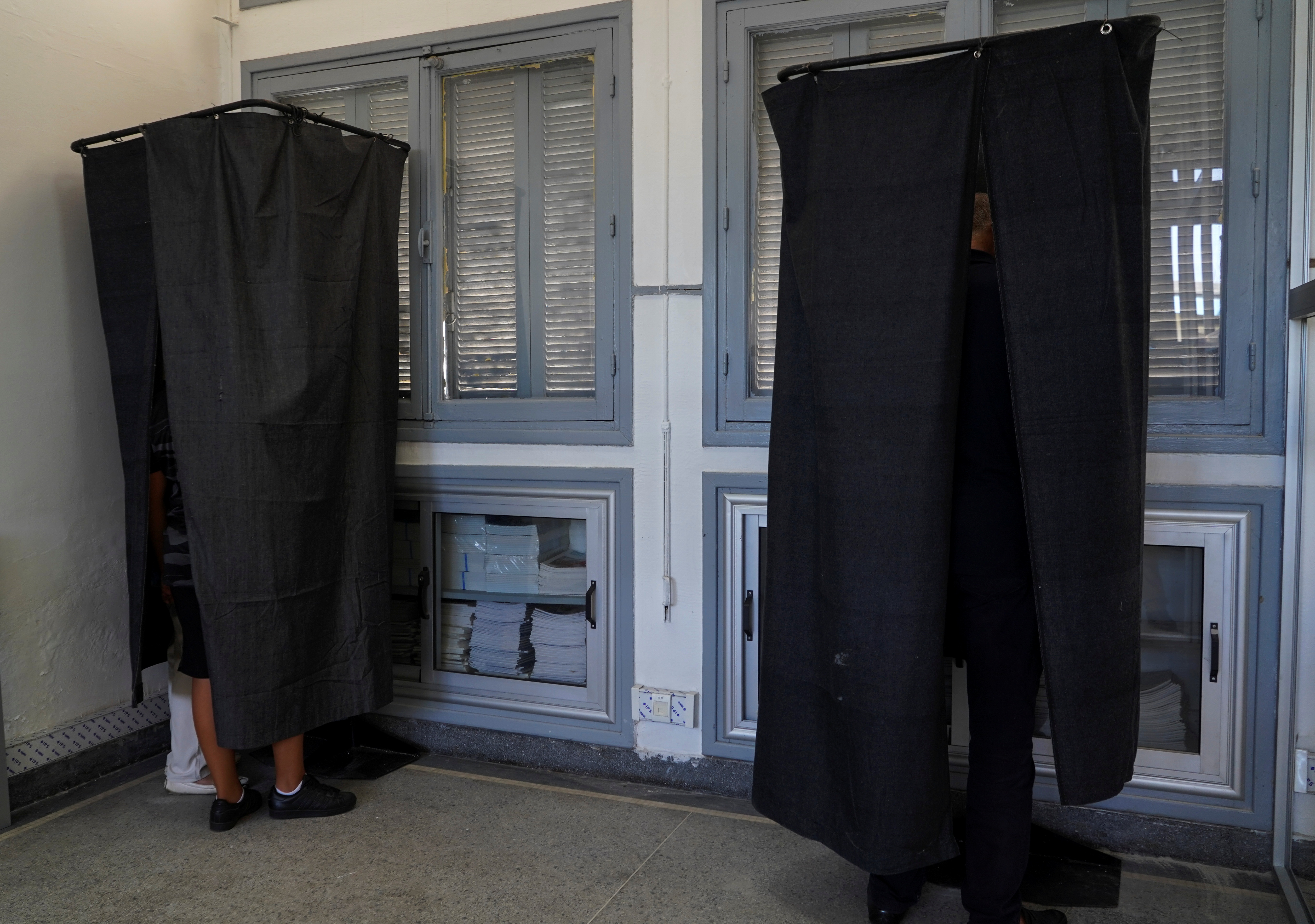 People stand behind curtains in voting booths during parliamentary and local elections, in Casablanca