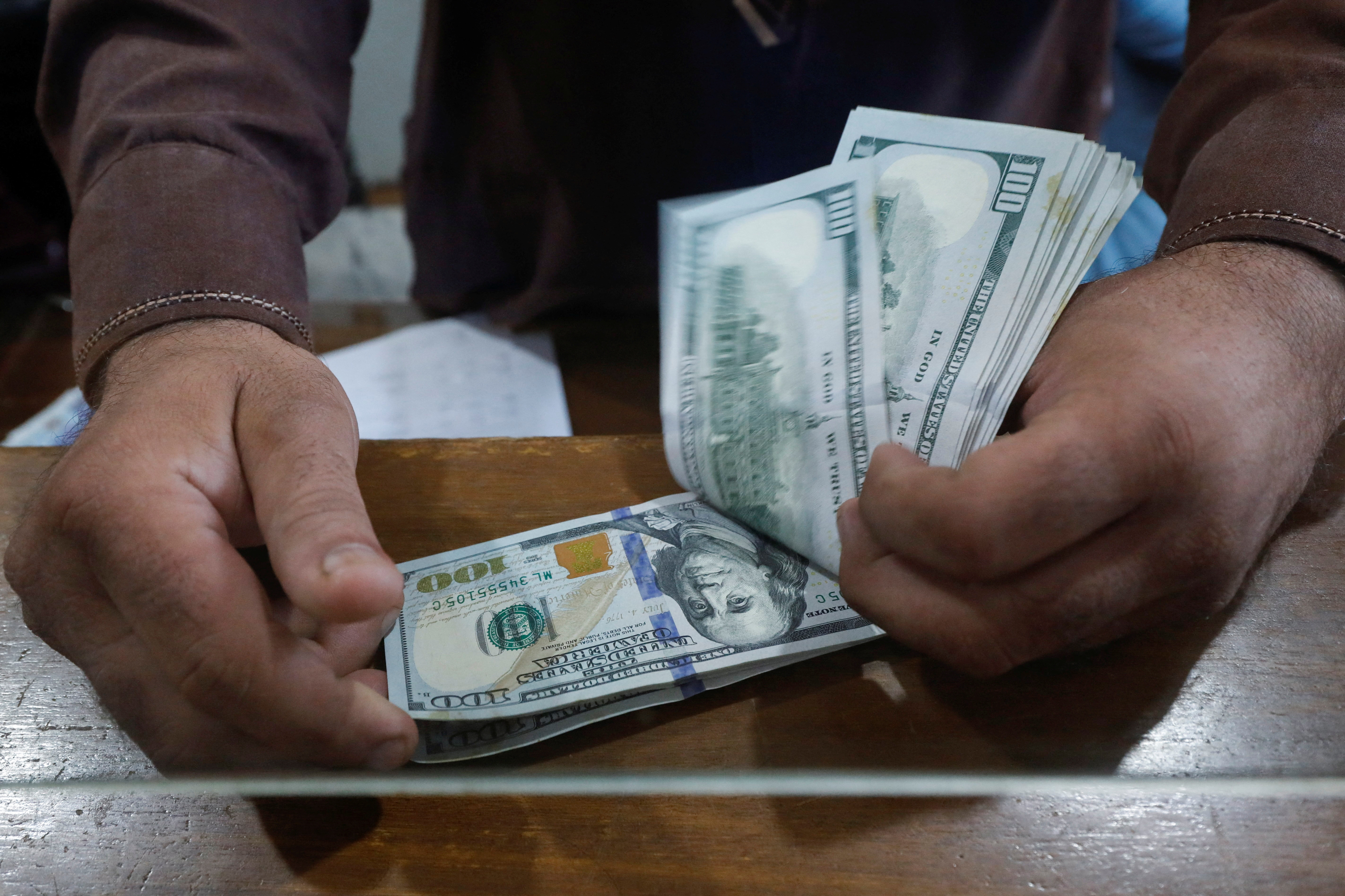 Employee of a foreign exchange shop counts U.S. dollar banknotes in Karachi