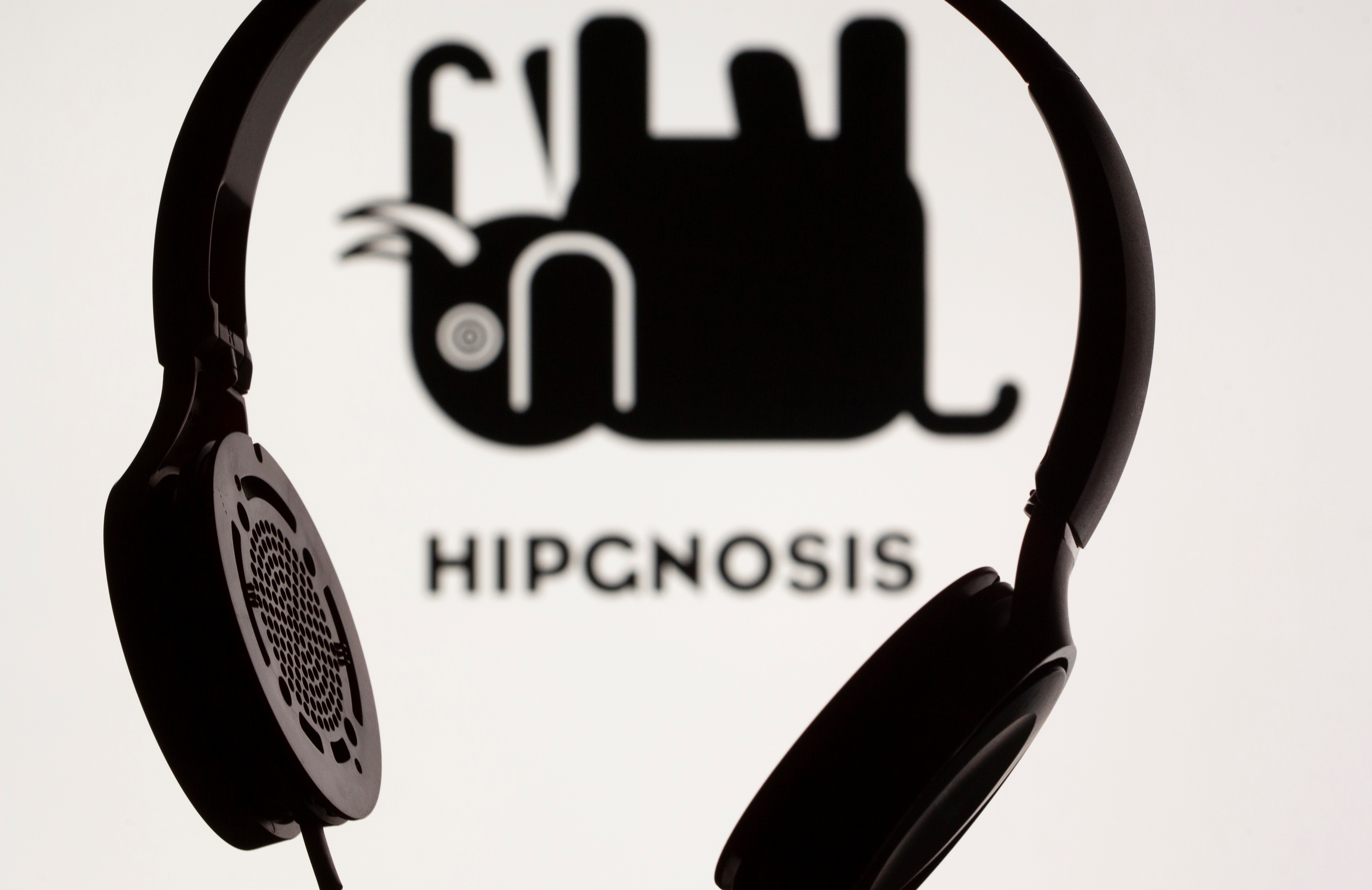 Headset seen in front of displayed Hipgnosis logo in this illustration taken