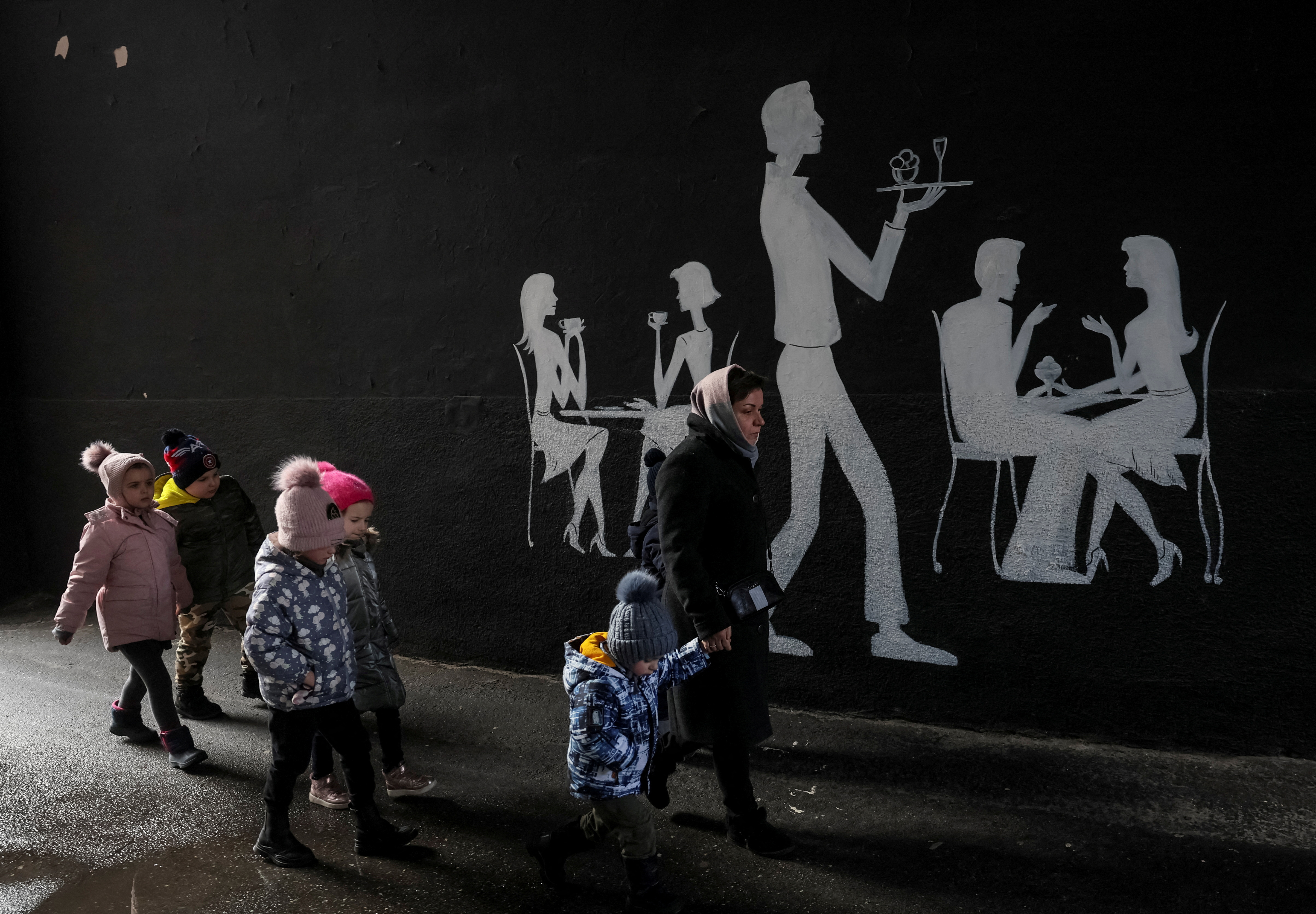Kindergarten employee leads children to a bomb shelter during an air raid in central Kyiv