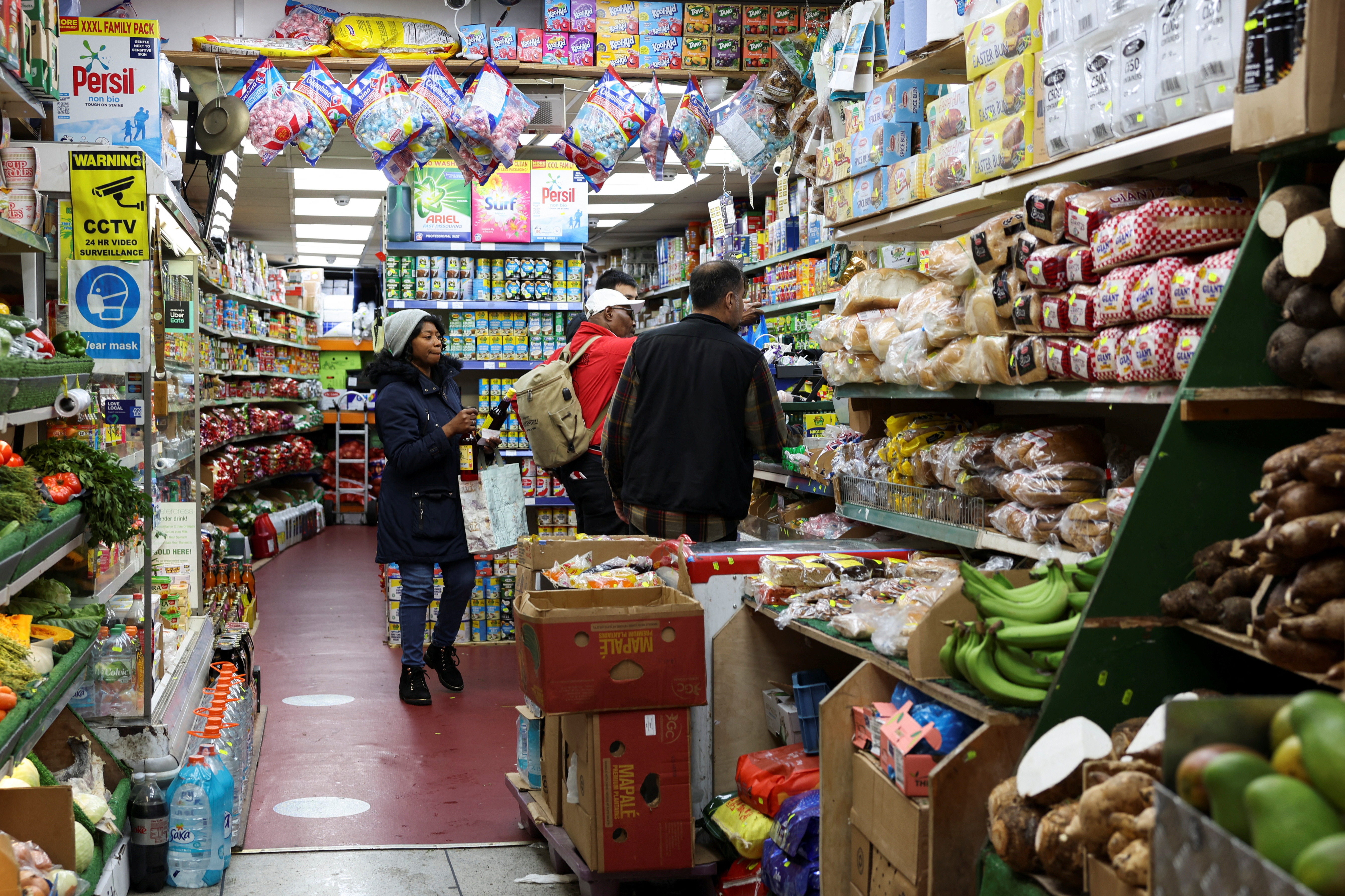 People shop at a grocery market, in London