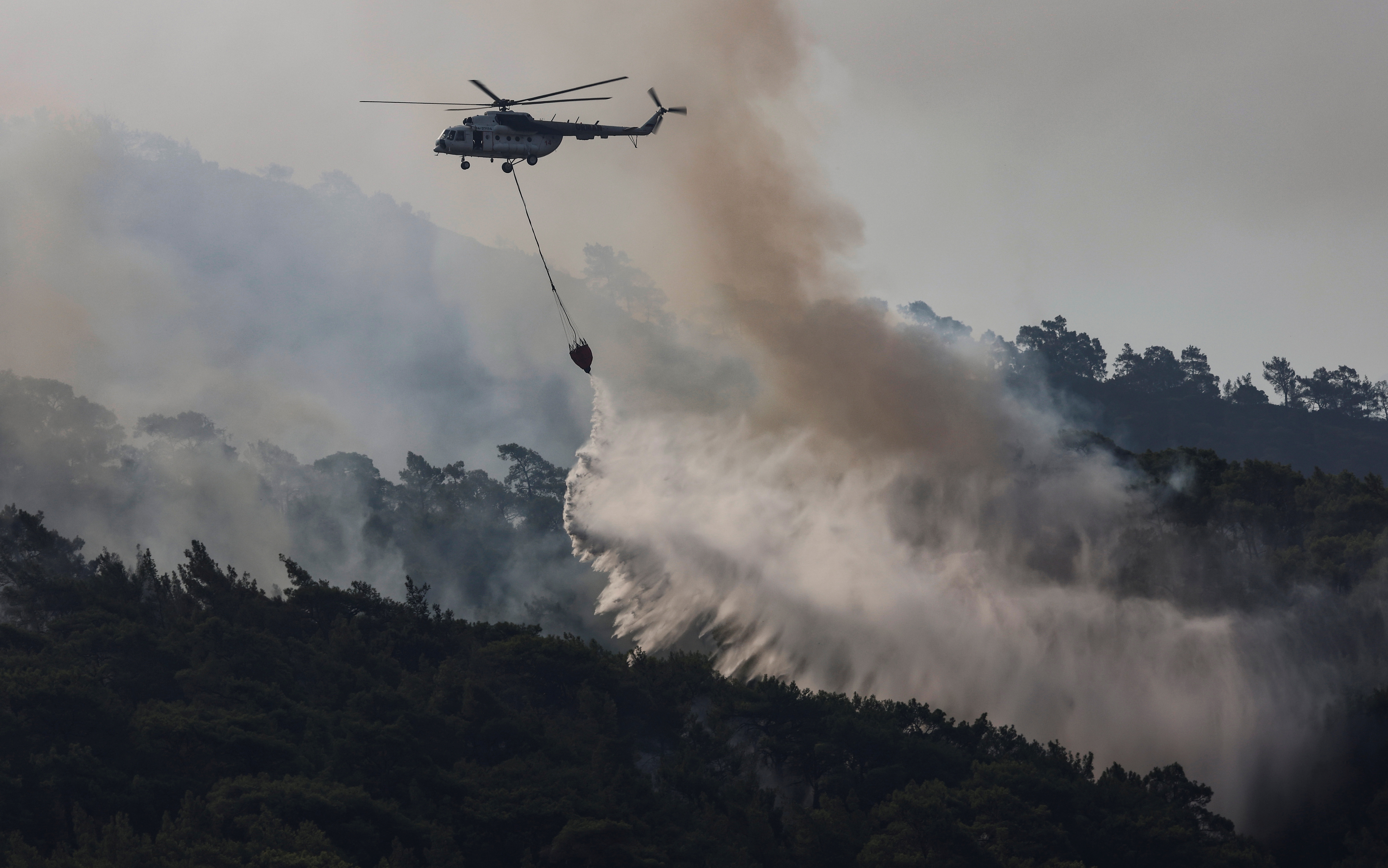 A firefighting helicopter drops water to a wildfire near Marmaris, Turkey, August 2, 2021. REUTERS/Umit Bektas
