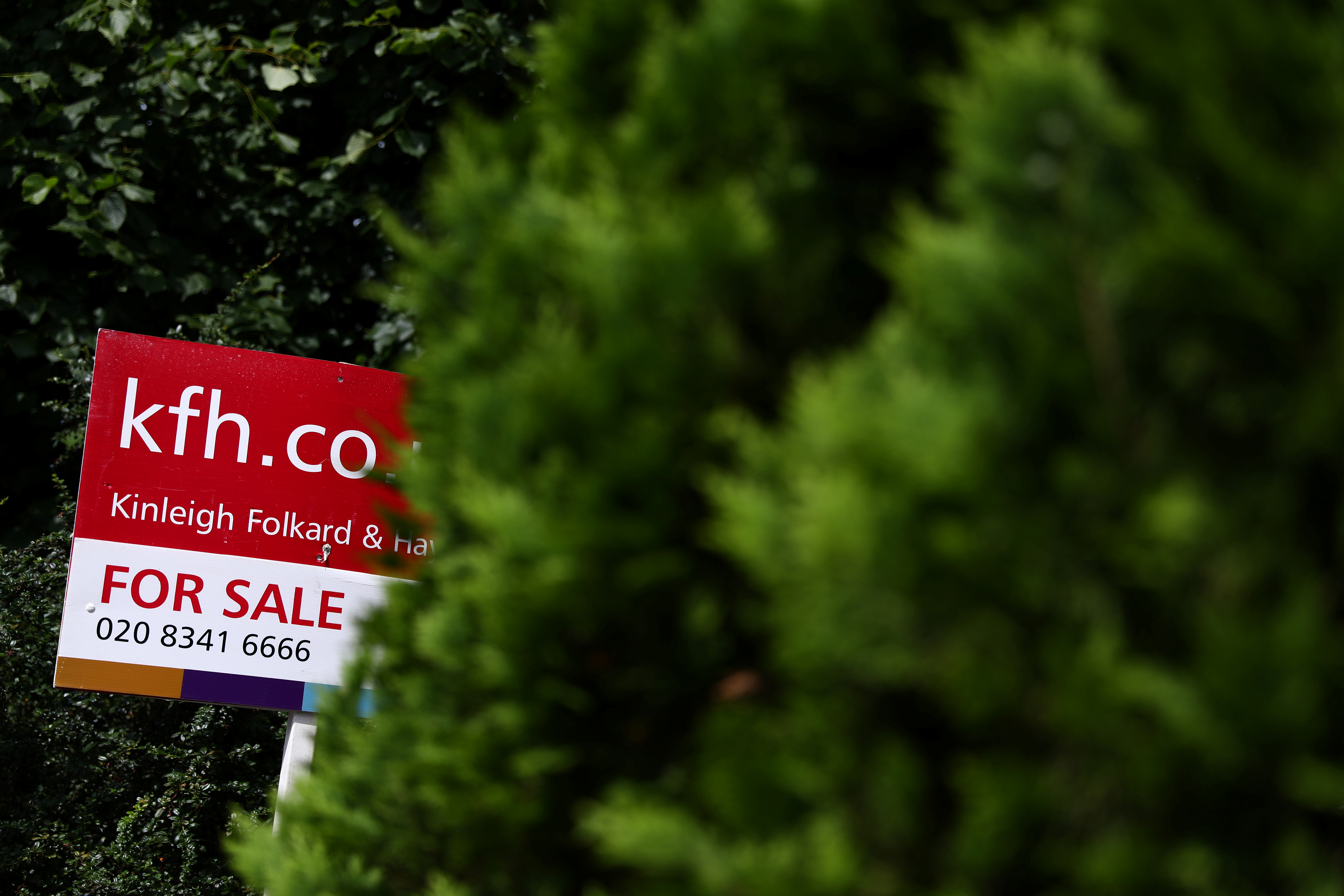 An estate agent board is displayed outside a property in London