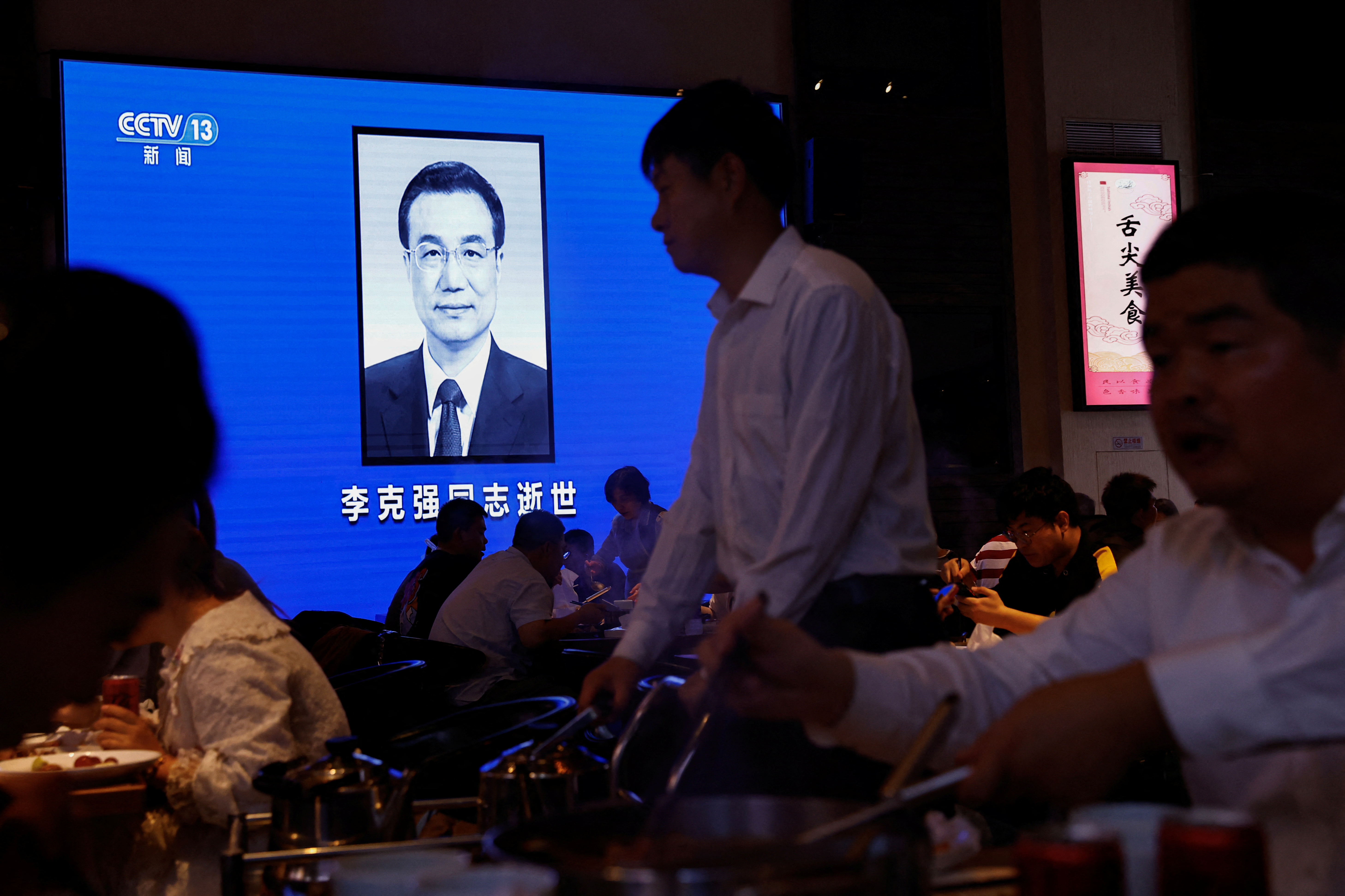 Screen broadcasts obituary of China's former Premier Li during evening news, following his death, at a restaurant in Beijing