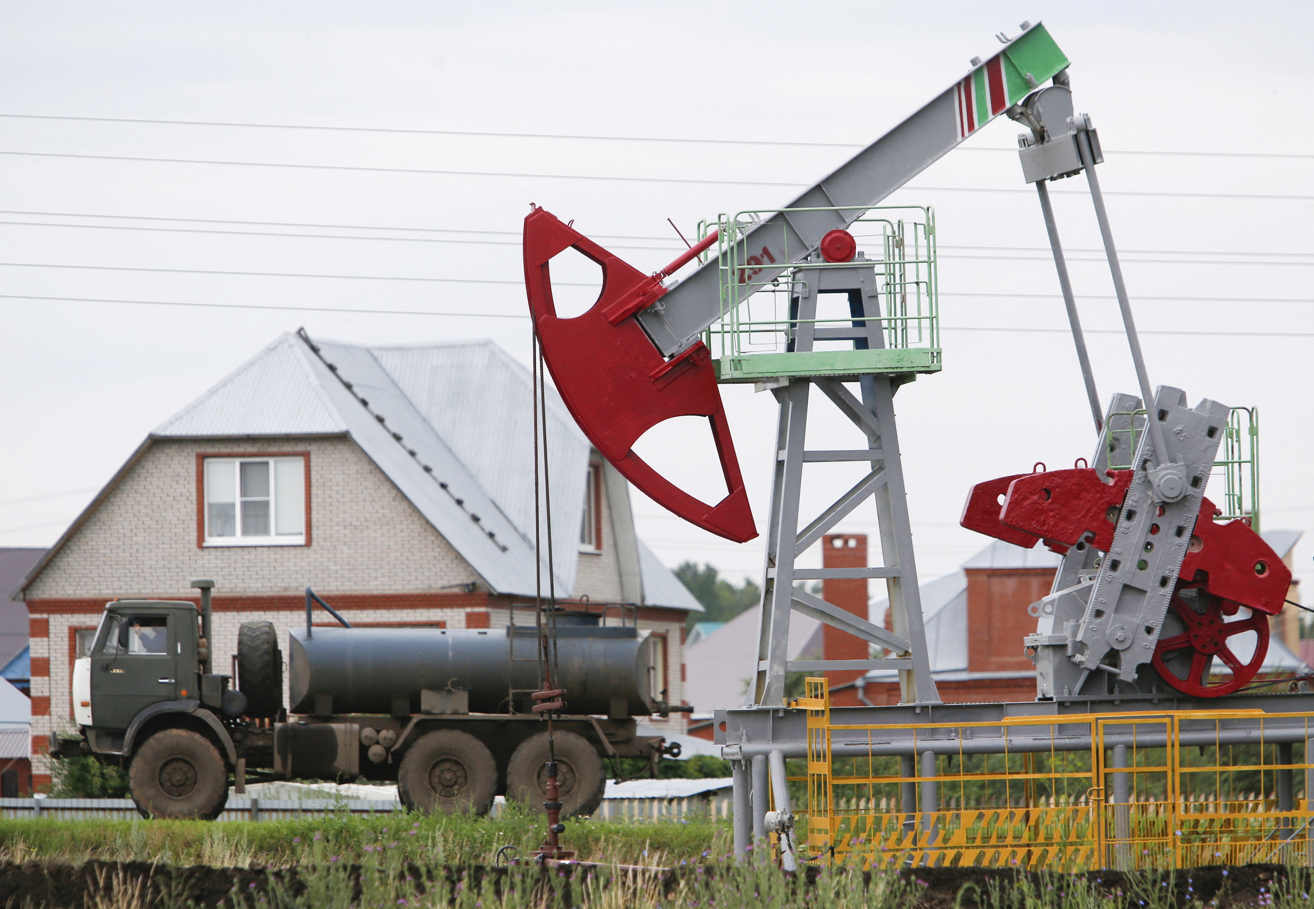 A fuel tanker truck drives past a pump jack at an oil field Sergeyevskoye owned by Bashneft company north from Ufa