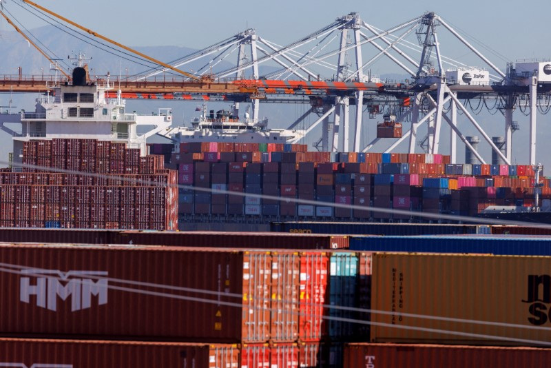 Stacked containers are shown as ships unload their cargo at the Port of Los Angeles