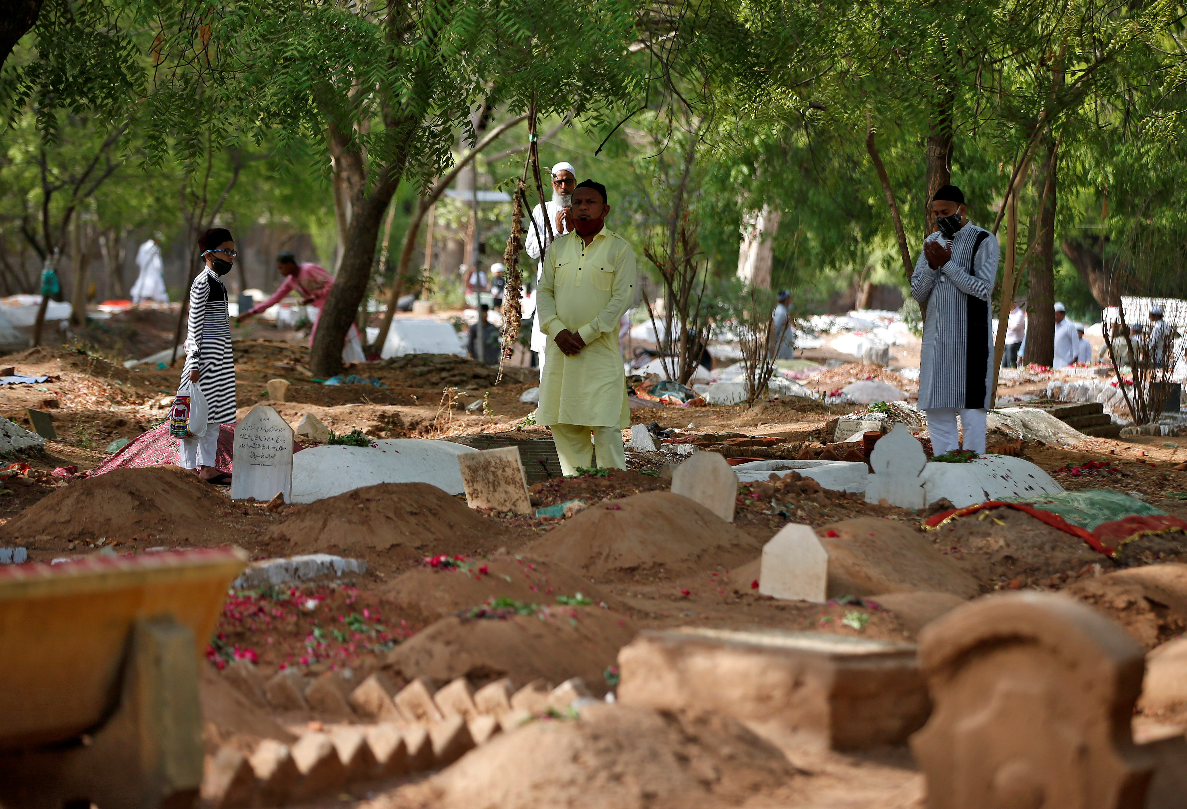 Muslims pray next to the graves of their relatives including those who died from the coronavirus disease (COVID-19), on the occasion of the Eid al-Fitr amidst the spread of the disease in Ahmedabad