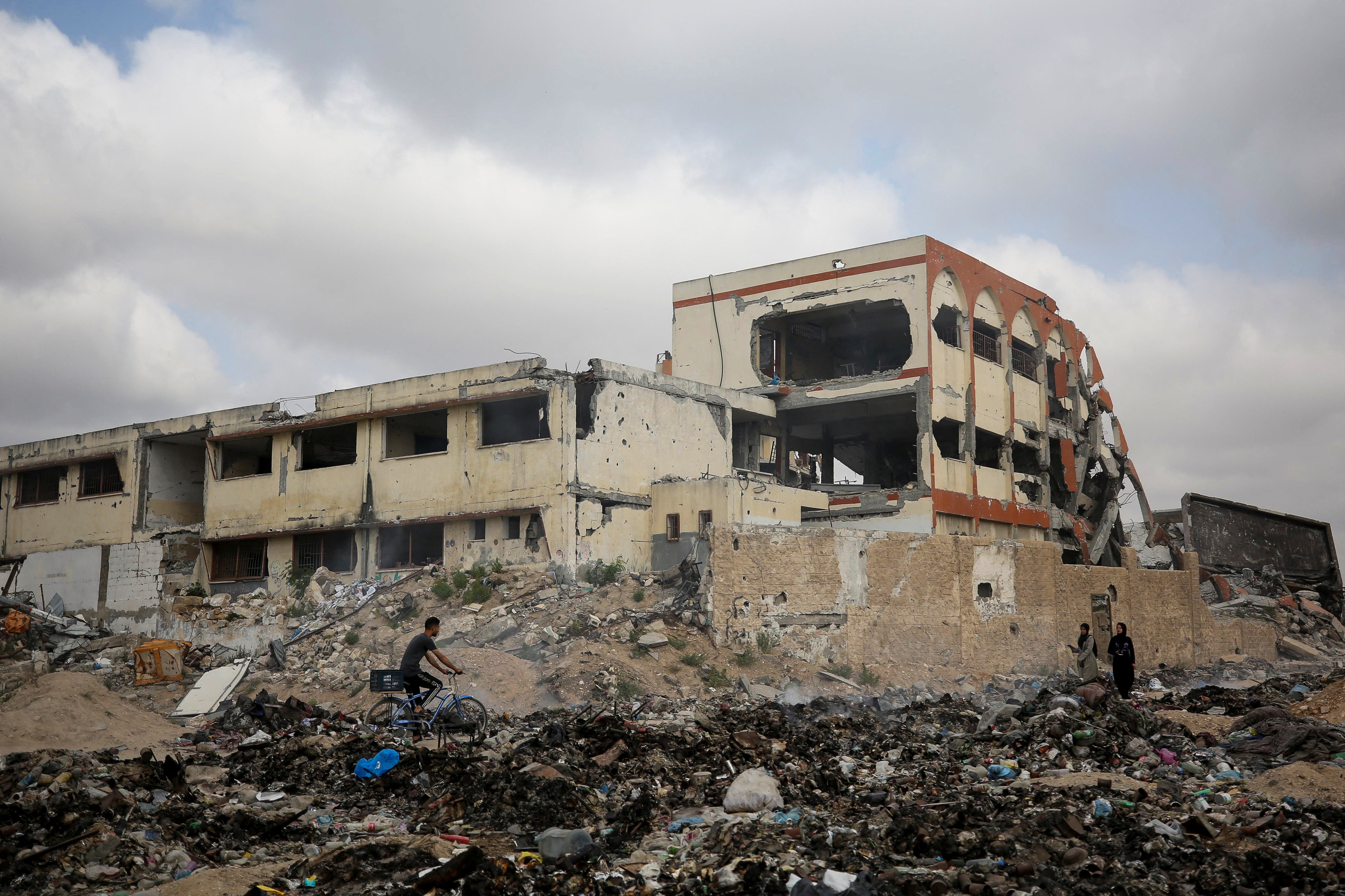 Palestinians pass by a school destroyed during Israel's military offensive, in Gaza City