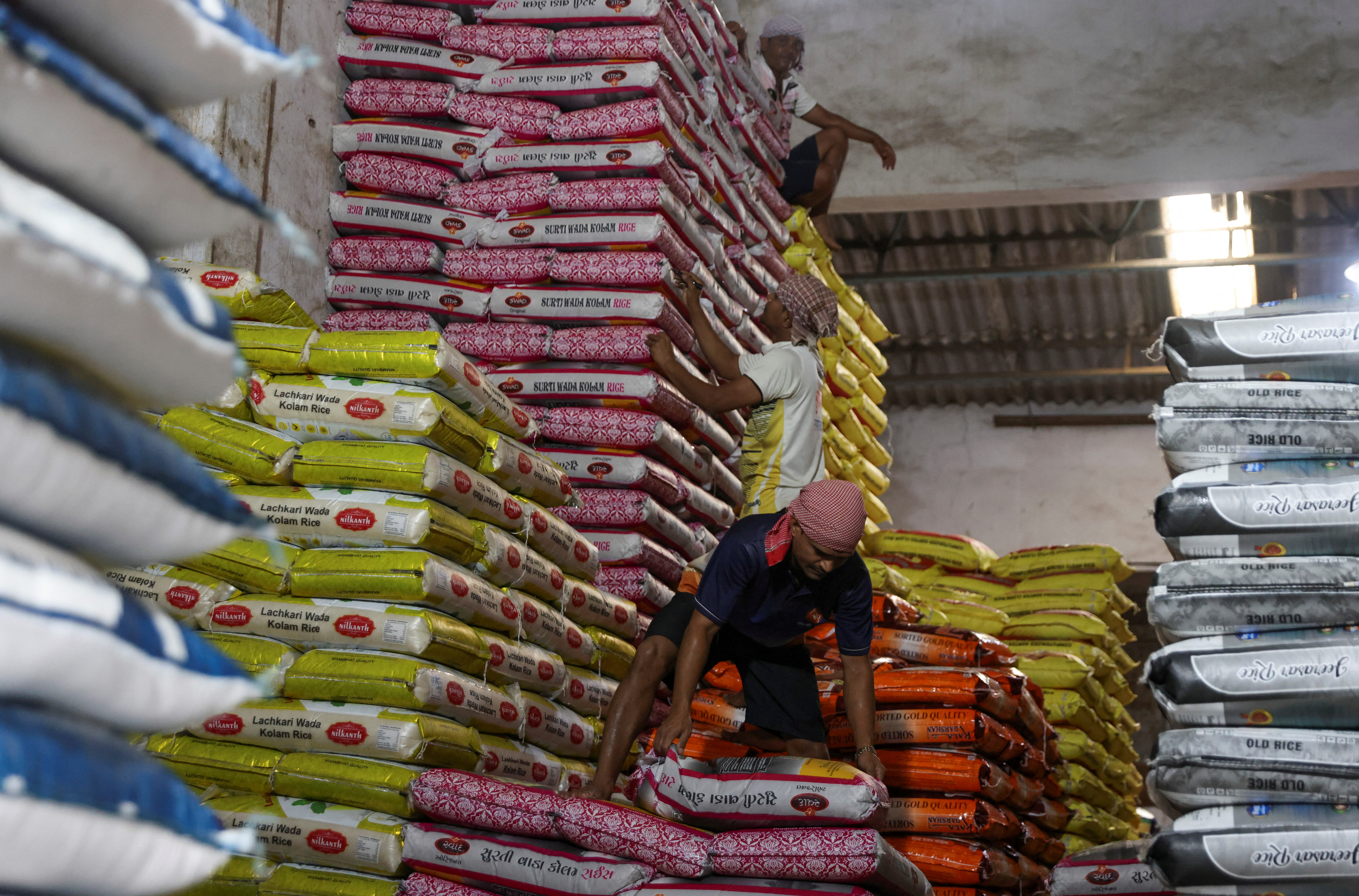 Workers stock rice packets inside a store room, at a wholesale market in Navi Mumbai